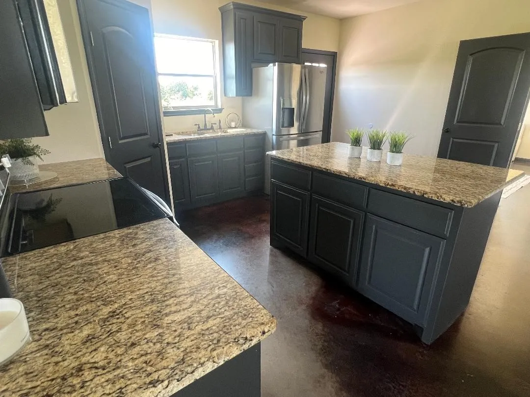 Kitchen featuring a kitchen island, light stone counters, concrete floors, and range with electric cooktop