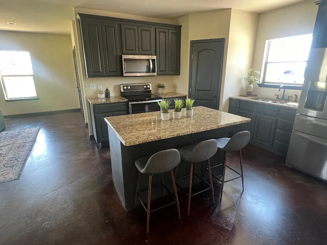 Kitchen with concrete flooring, healthy amount of natural light, stainless steel appliances, and a kitchen island