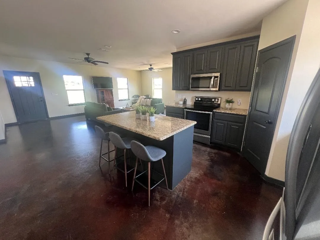 Kitchen with appliances with stainless steel finishes, a breakfast bar area, a center island, concrete flooring, and open floor plan