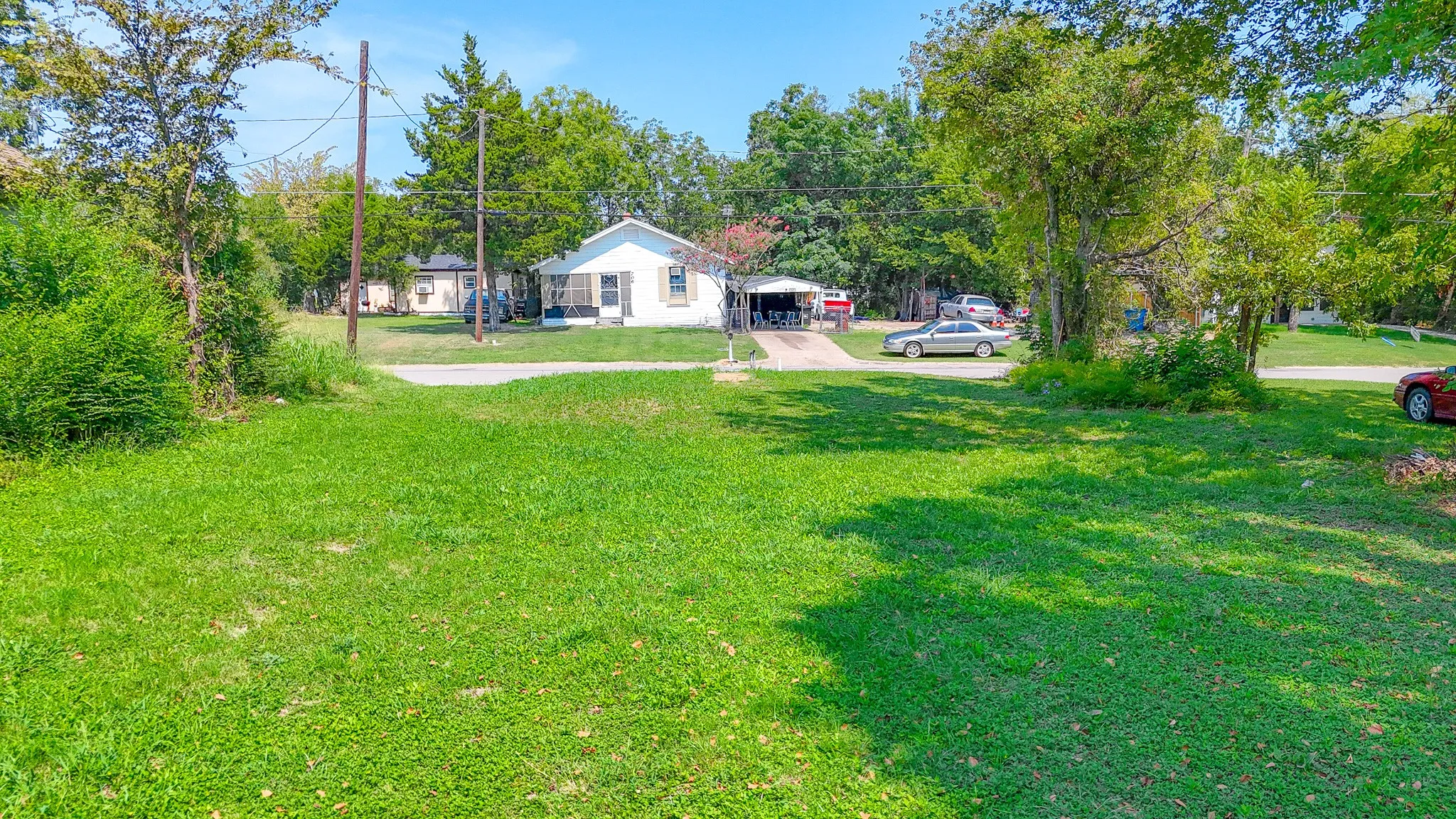 View of grassy yard with view of wooded area