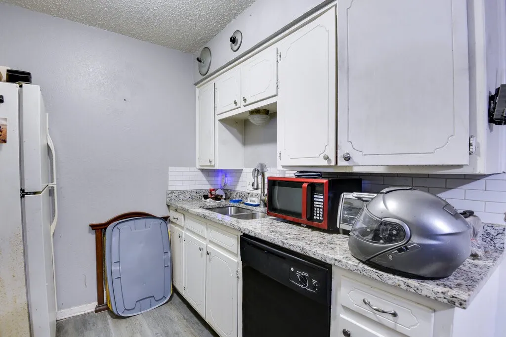 Left Unit Kitchen featuring freestanding refrigerator, backsplash, a textured ceiling, dishwasher, and white cabinets