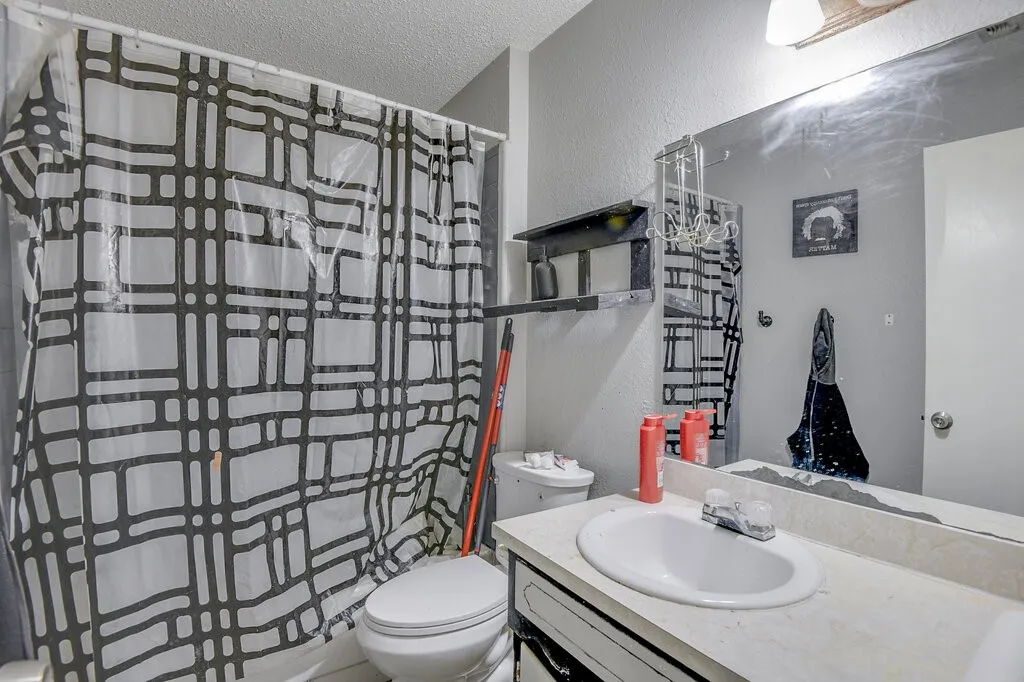 Left Unit Full bath with a textured wall, a textured ceiling, and vanity