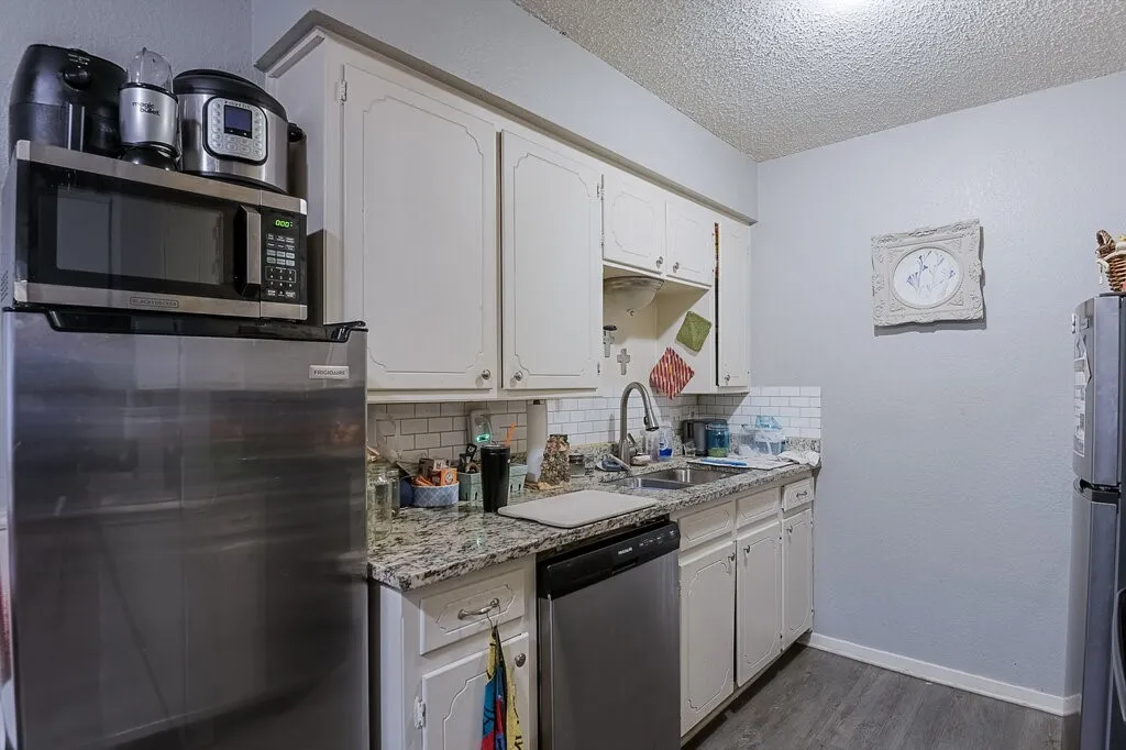 Right Unit Kitchen featuring backsplash, a textured ceiling, white cabinetry, appliances with stainless steel finishes, and dark wood-style floors