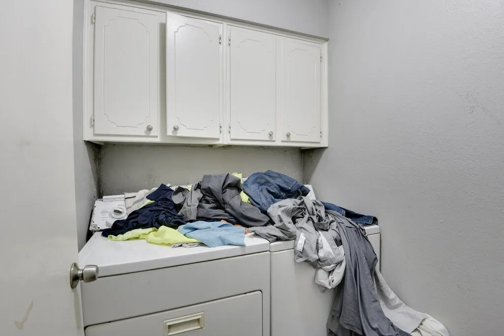 Left Unit Laundry room with cabinet space, washer and clothes dryer, and a textured wall
