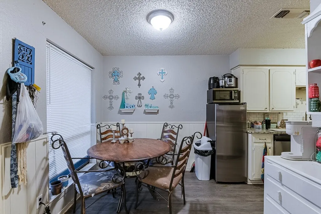 Right Unit Dining room with a textured ceiling, dark wood-type flooring, and a wainscoted wall
