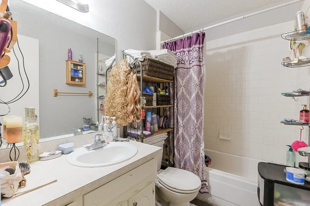Right Unit Bathroom featuring shower / bathtub combination with curtain, vanity, and a textured ceiling