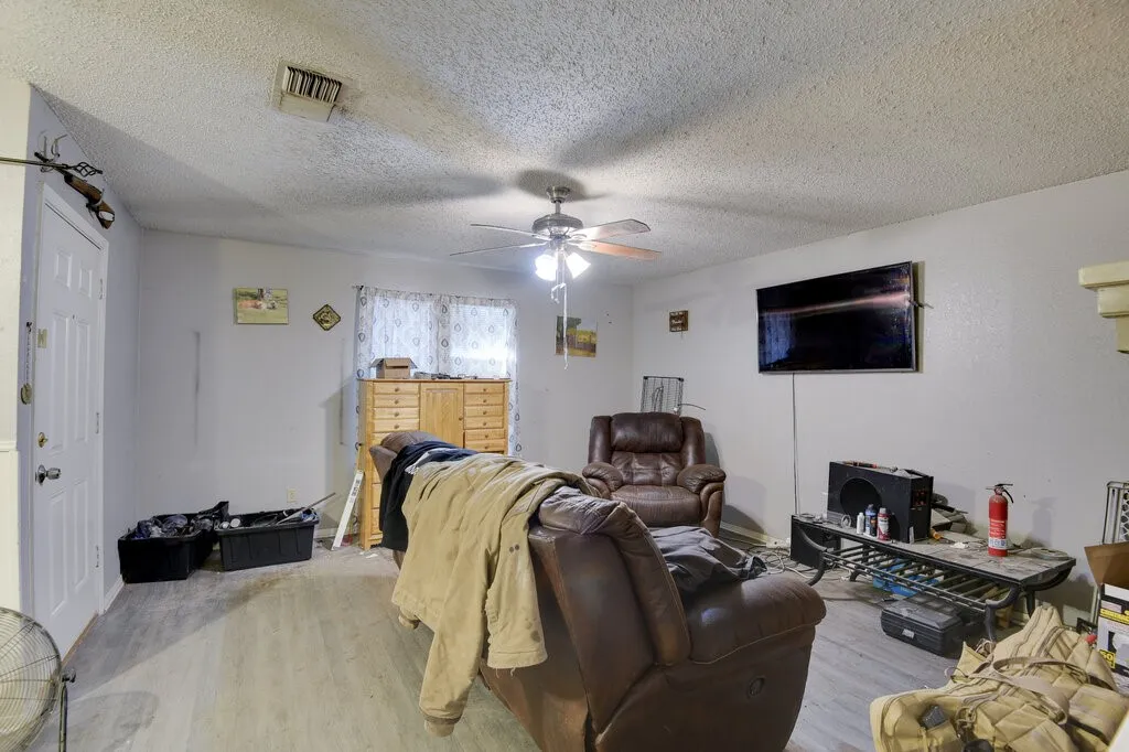 left unit Living area featuring light wood-style floors, a textured ceiling, and ceiling fan