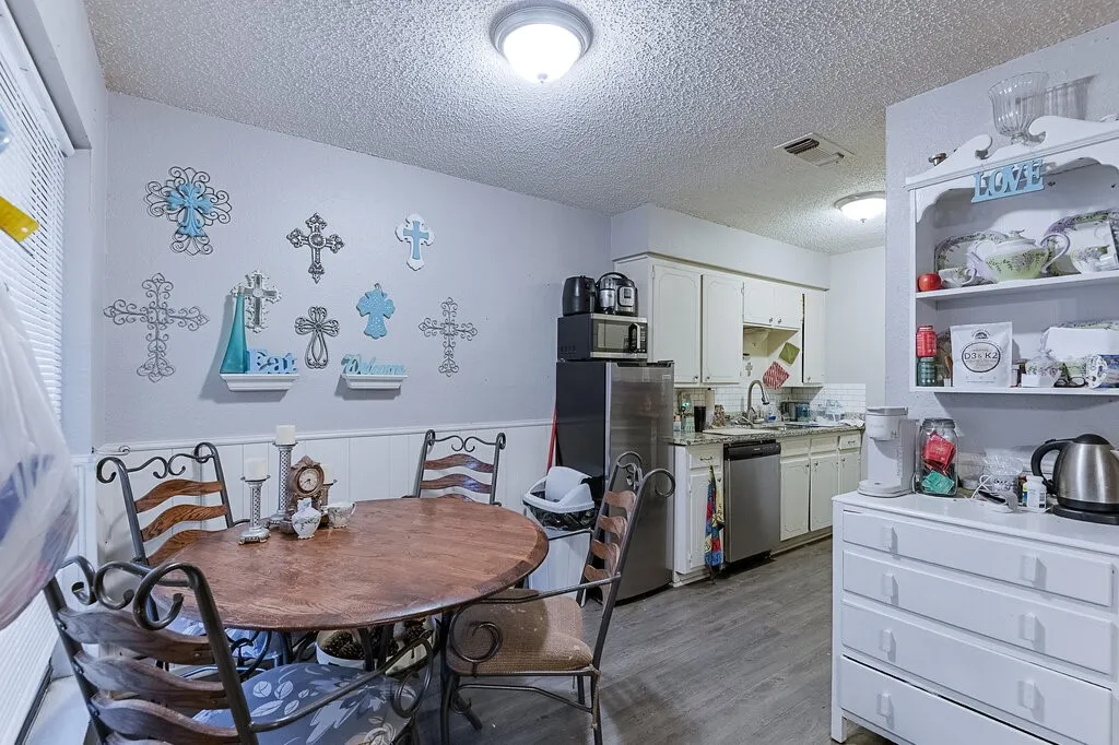 Right Unit Dining room featuring a textured ceiling, light wood-type flooring, and wainscoting
