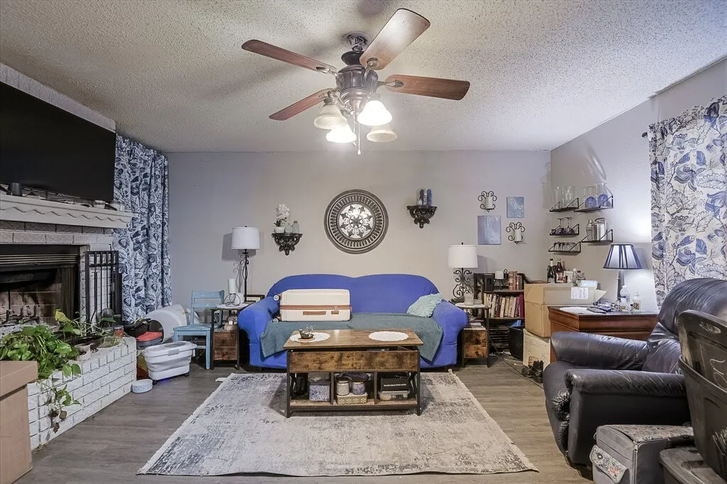Right Unit Living room with a textured ceiling, wood finished floors, ceiling fan, and a fireplace