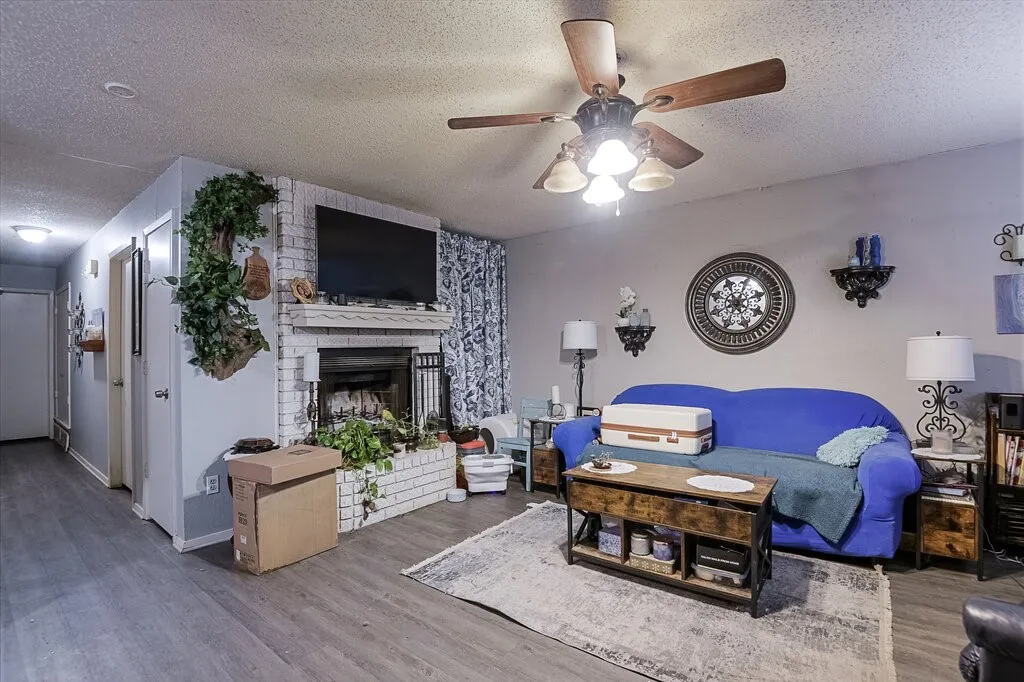 Right Unit Living room featuring a textured ceiling, wood finished floors, a brick fireplace, and ceiling fan