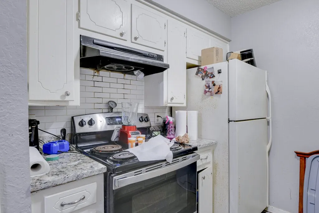 Left Unit Kitchen featuring stainless steel range with electric cooktop, light countertops, white cabinets, and a textured wall