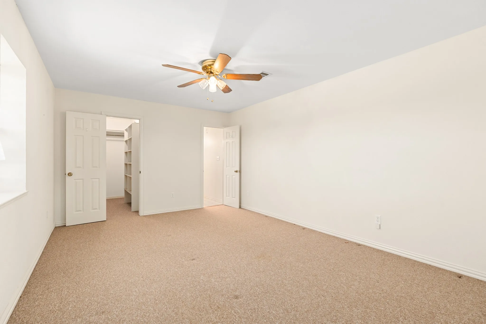 Unfurnished bedroom with carpet floors, a spacious closet, and a ceiling fan