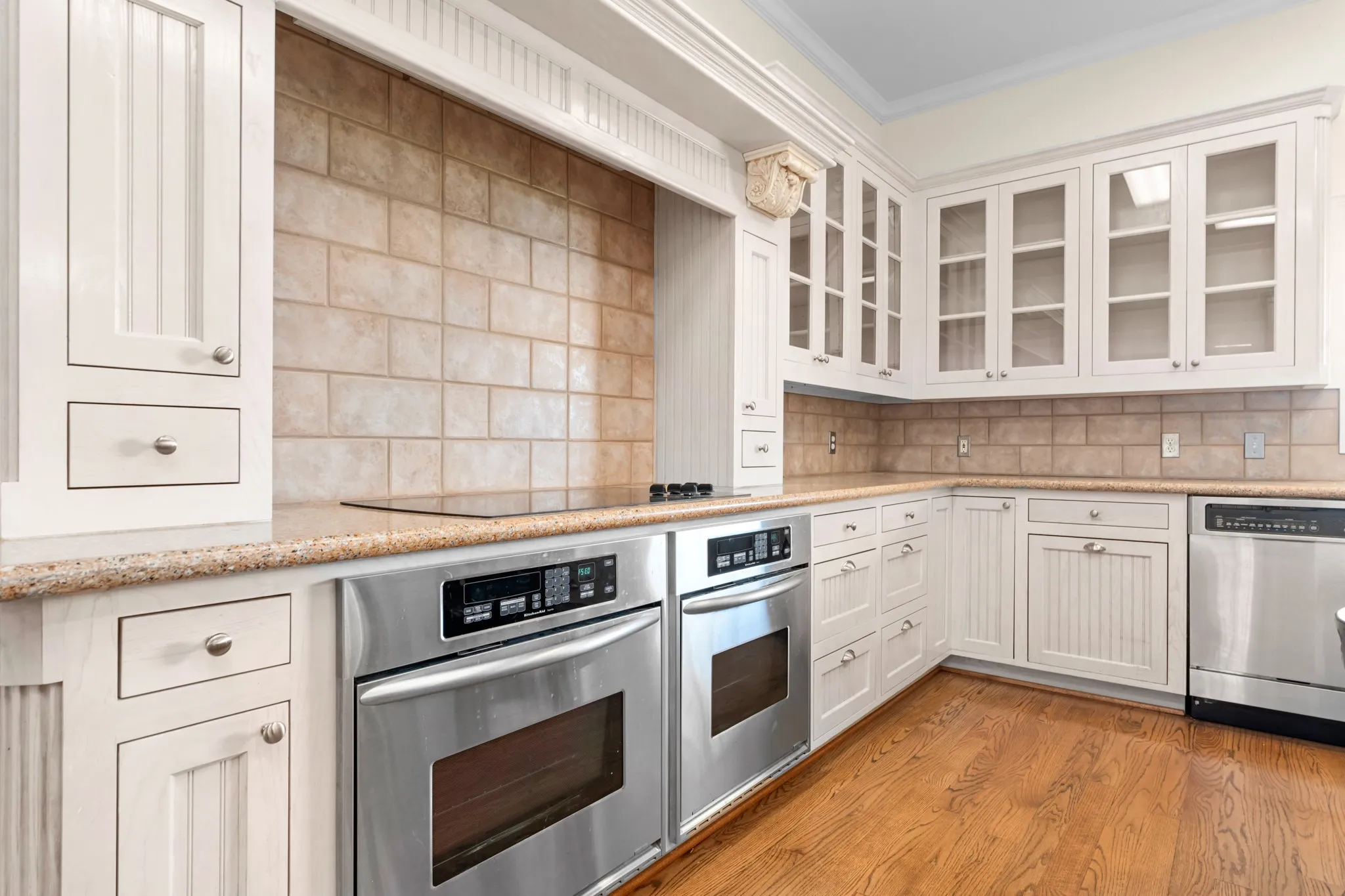 Kitchen with tasteful backsplash, appliances with stainless steel finishes, light wood-style flooring, white cabinets, and ornamental molding