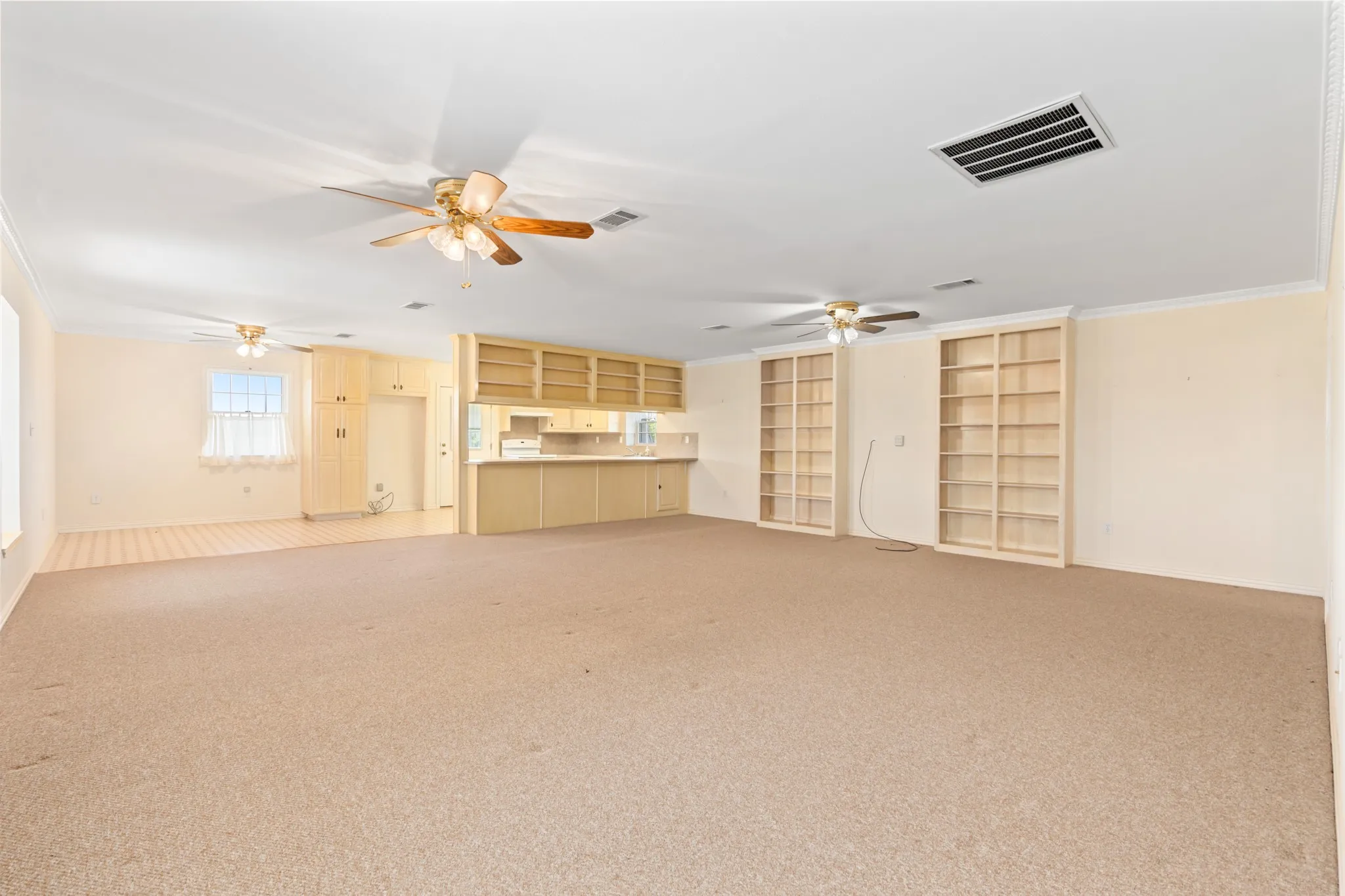 Unfurnished living room with ornamental molding, light carpet, and a ceiling fan