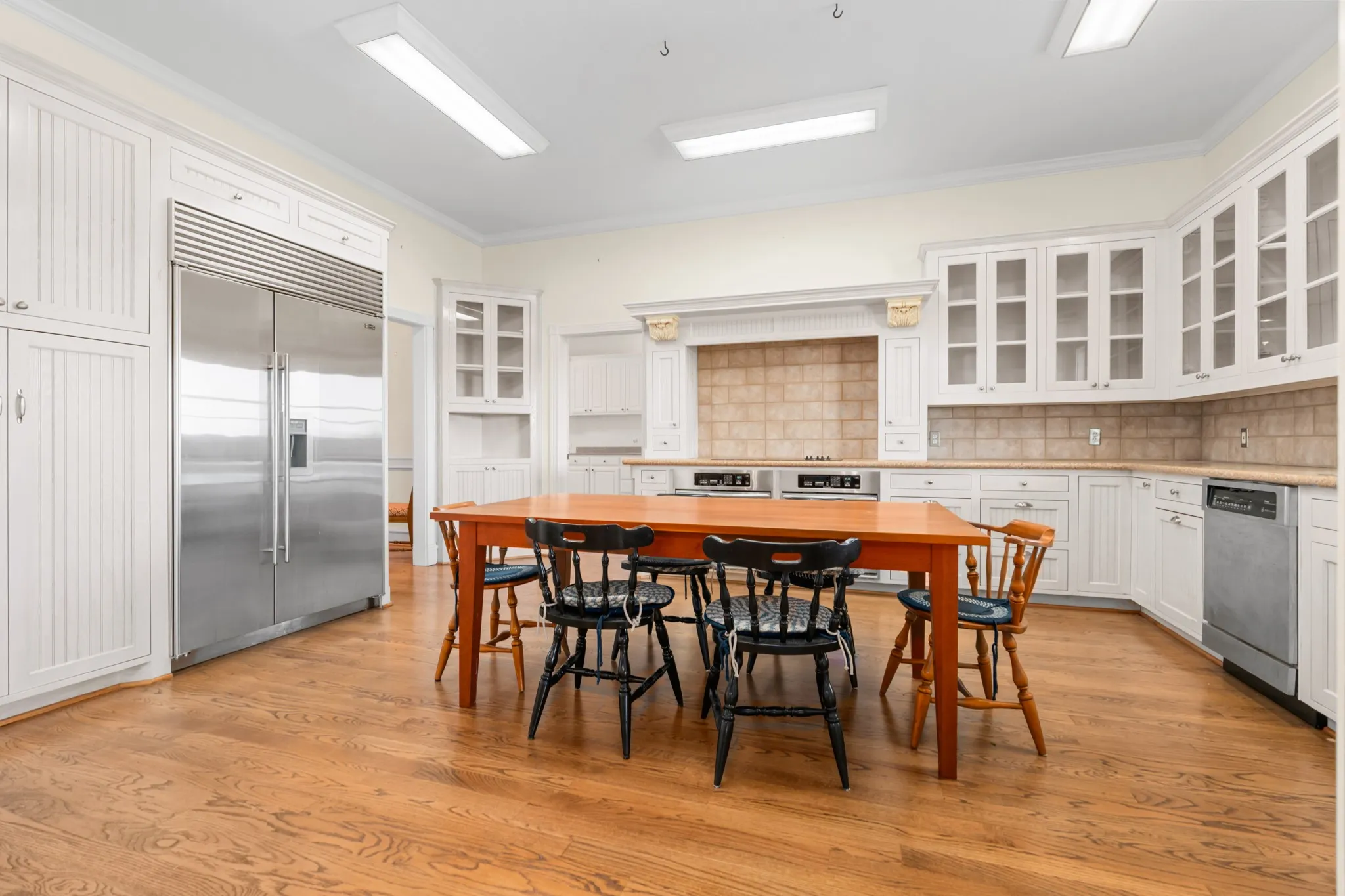 Kitchen with glass insert cabinets, white cabinets, crown molding, backsplash, and appliances with stainless steel finishes