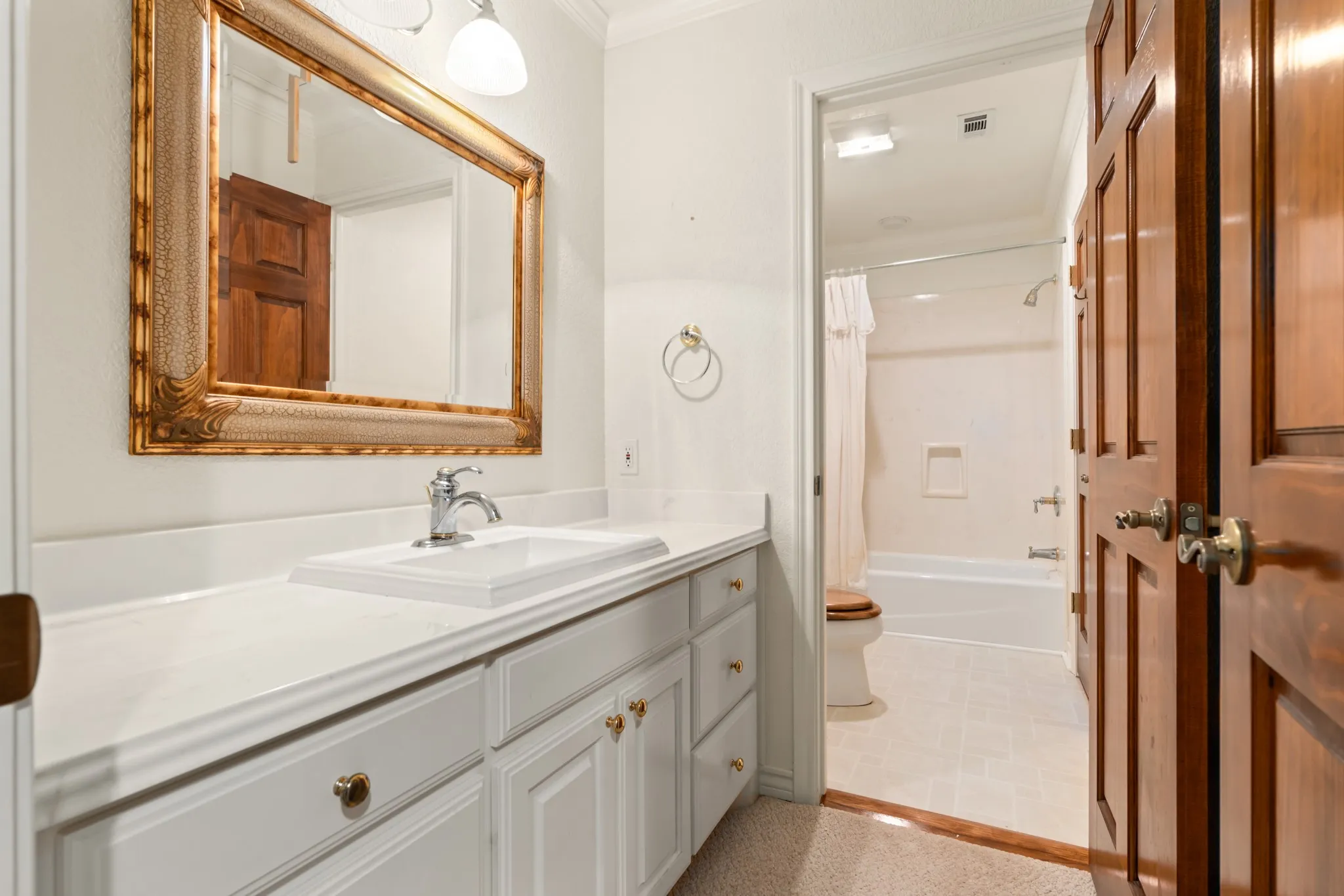 Bathroom with vanity, shower / bath combination with curtain, and crown molding