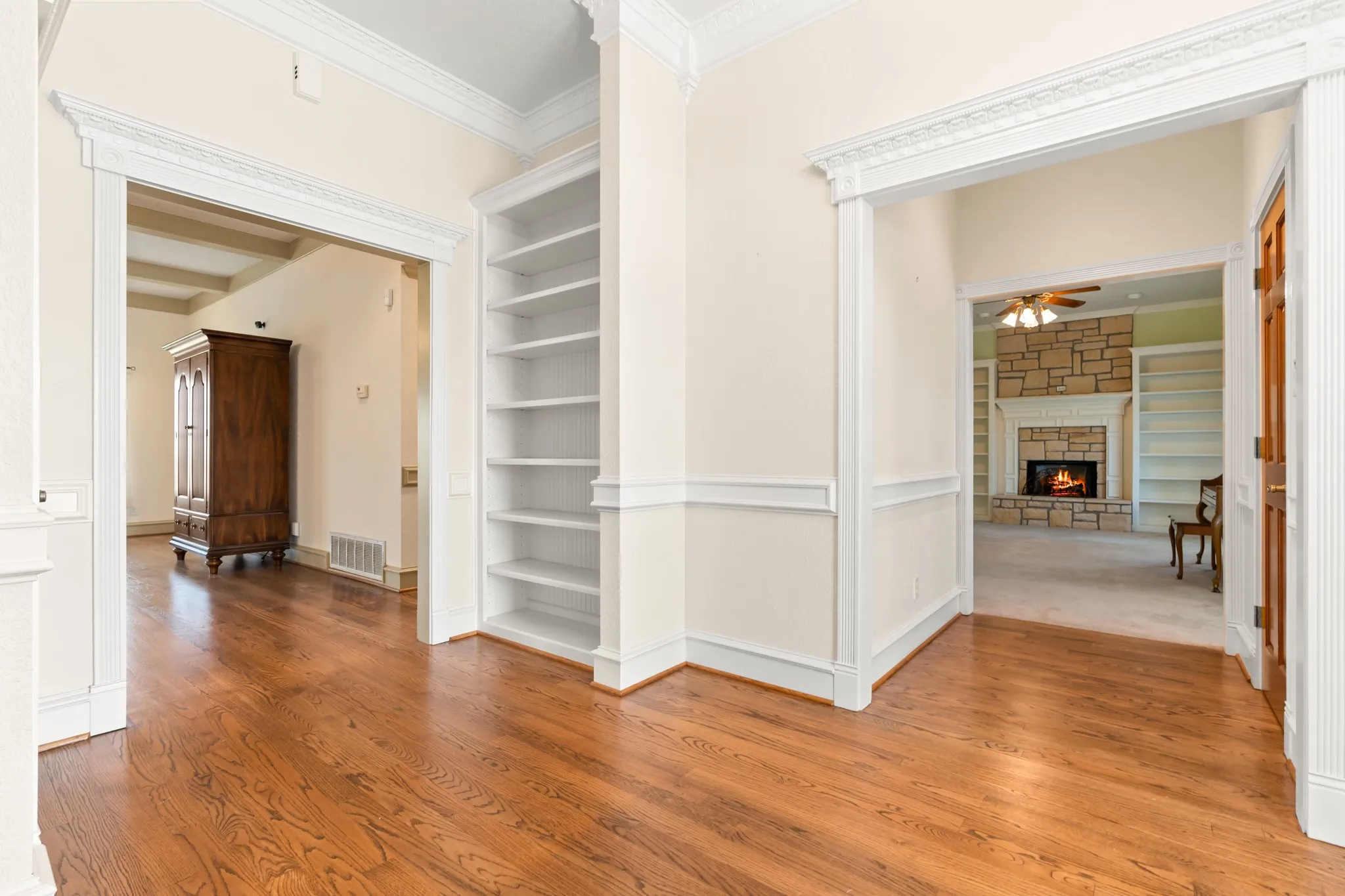 Hall featuring built in shelves, wood finished floors, and crown molding