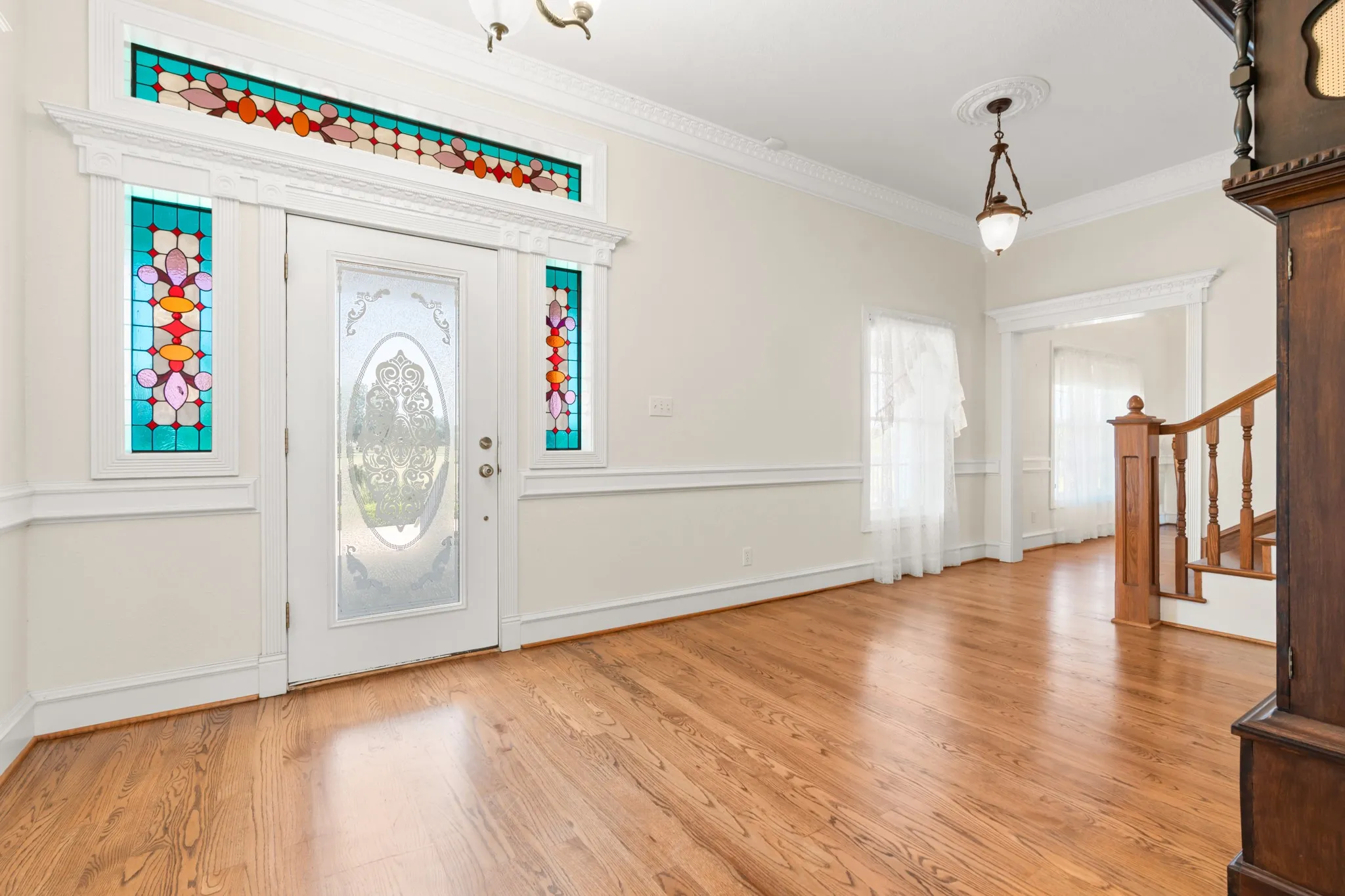 Entryway with stairway, crown molding, and light wood-style flooring