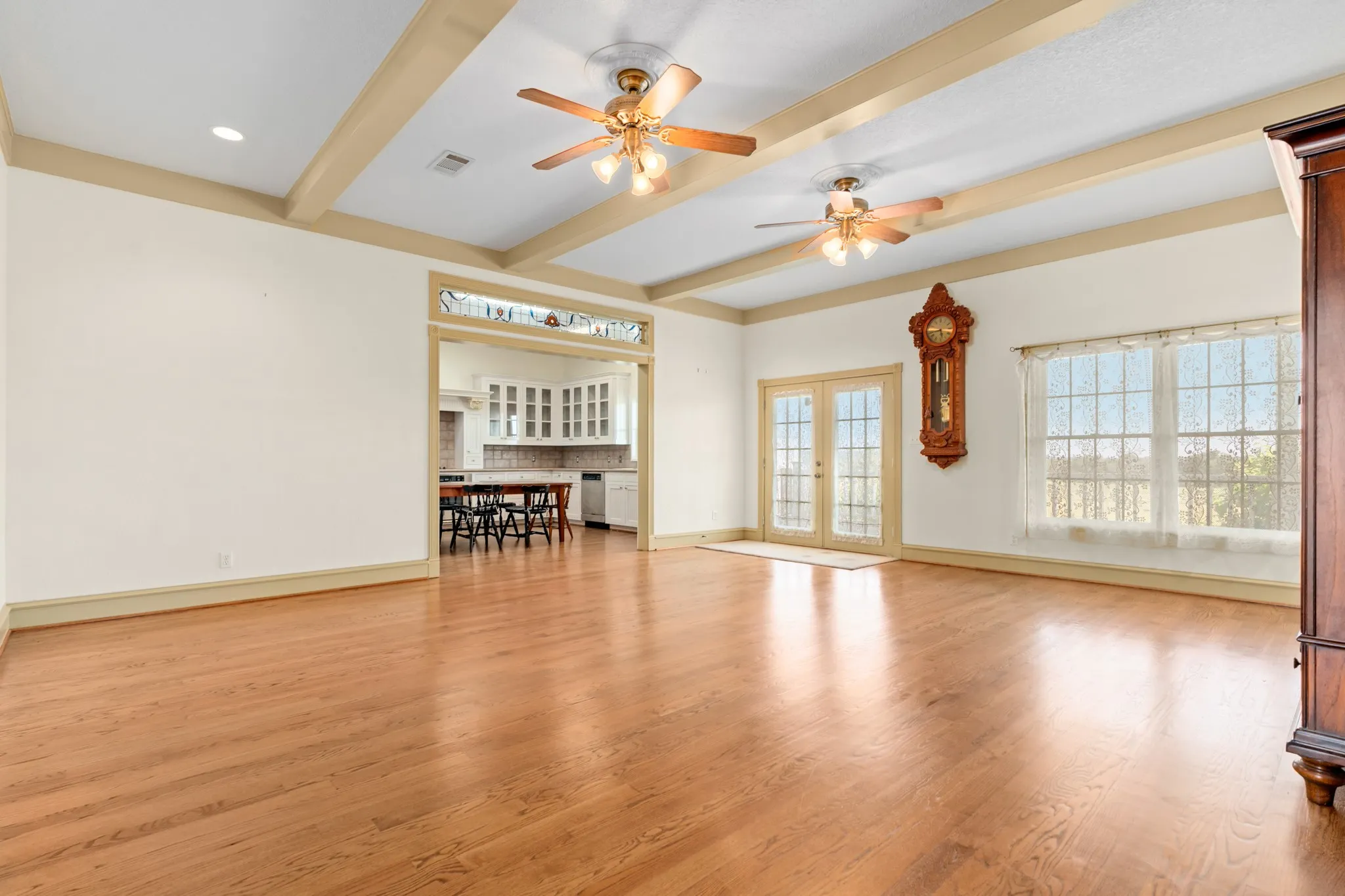 Unfurnished living room with light wood-type flooring, beam ceiling, french doors, and ceiling fan