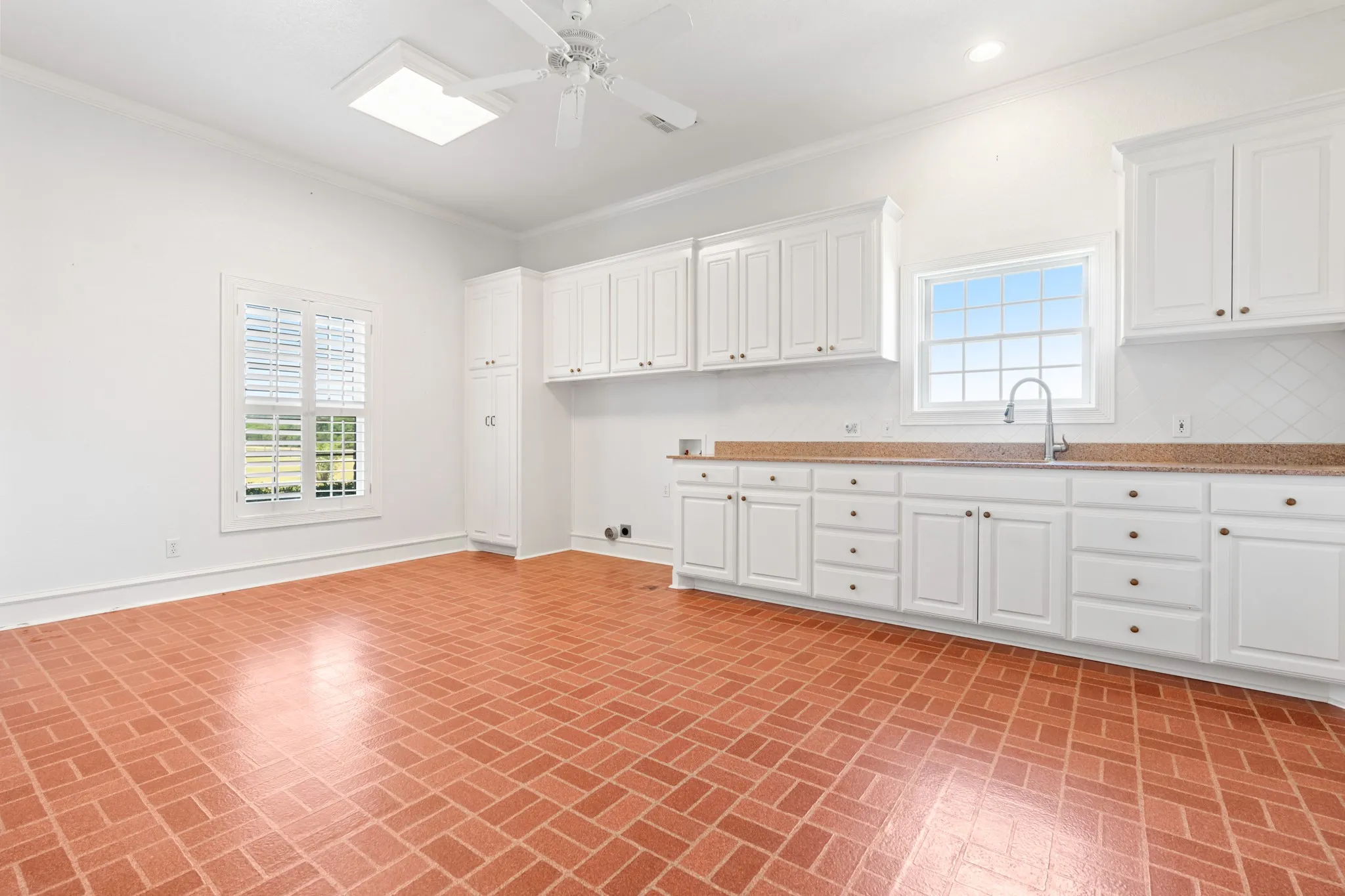 Kitchen featuring ornamental molding, white cabinets, brick patterned floors, and a ceiling fan