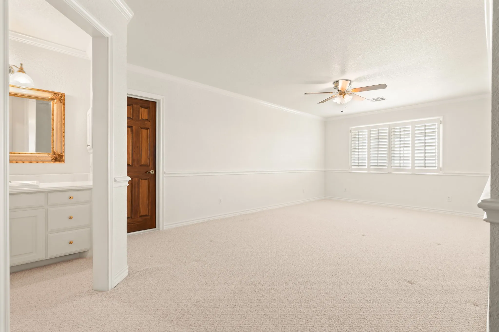 Empty room with light carpet, crown molding, and ceiling fan