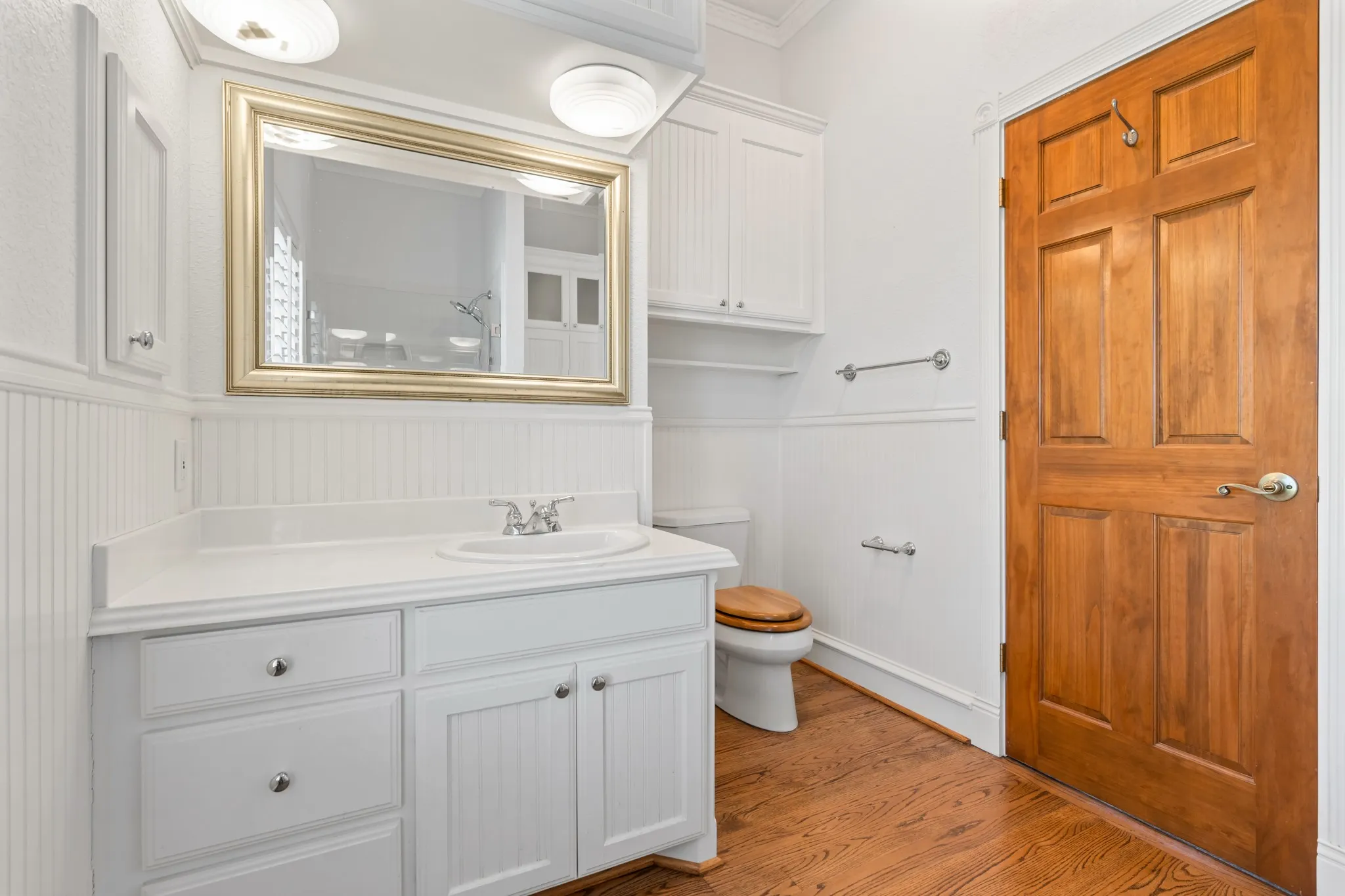 Full bathroom with light wood-style floors, vanity, a wainscoted wall, and a shower