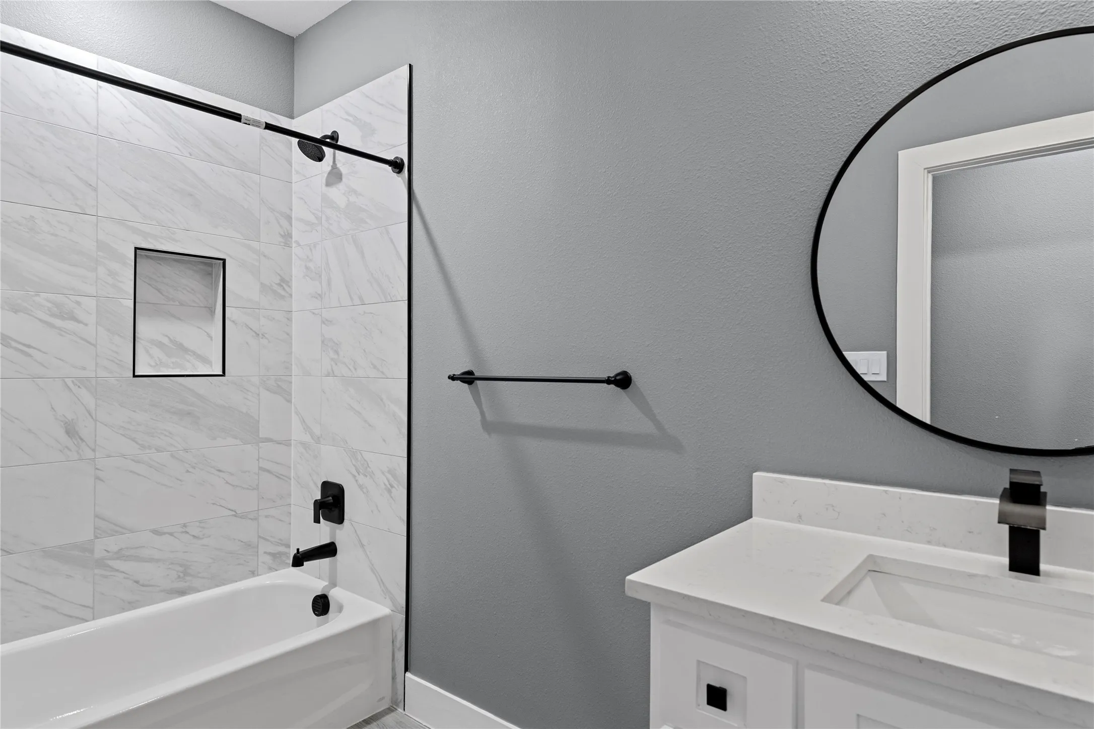 Full bathroom featuring a textured wall, bathing tub / shower combination, and vanity