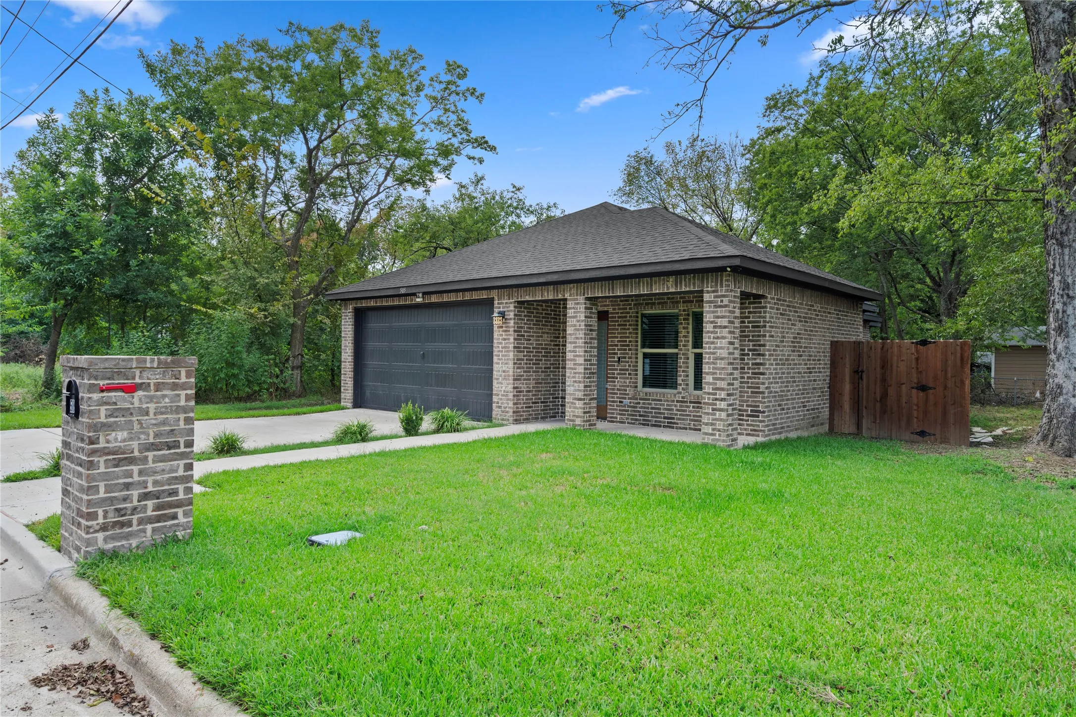 View of front of house featuring brick siding, a front lawn, concrete driveway, and a shingled roof