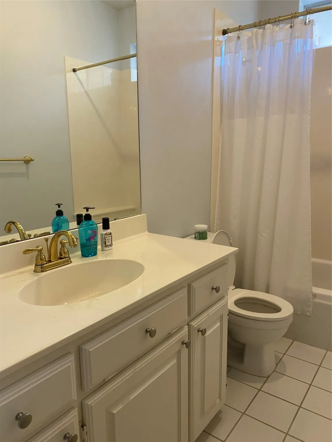 Bathroom with light tile patterned floors, vanity, and shower / bathtub combination with curtain
