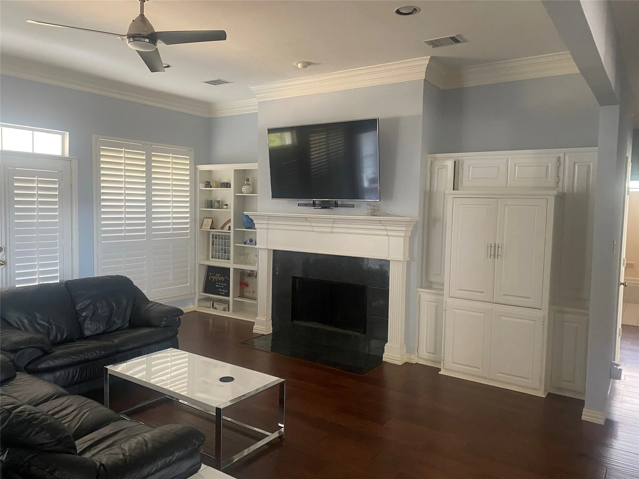 Living area with crown molding, a fireplace, dark wood finished floors, and a ceiling fan