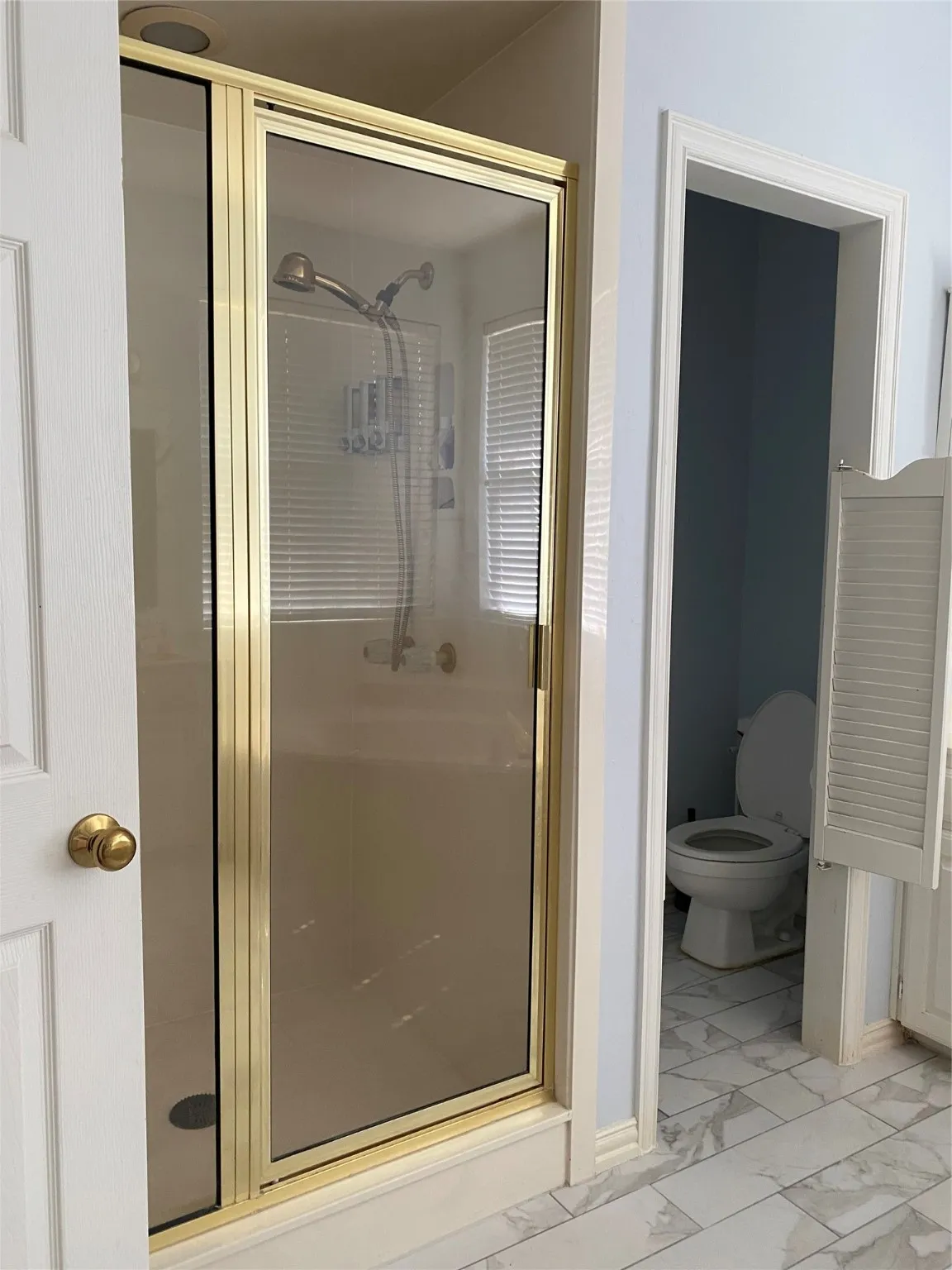 Bathroom with a shower stall and light marble finish flooring