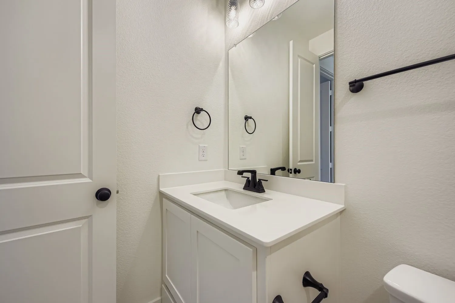 Half bathroom featuring a textured wall and vanity