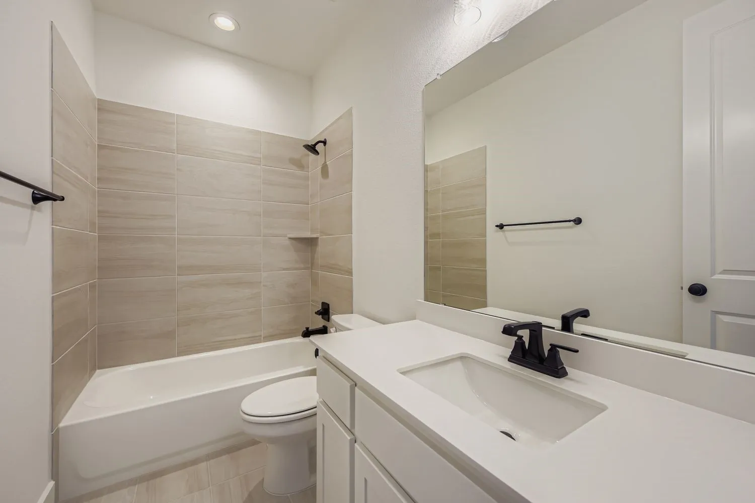Bathroom featuring washtub / shower combination, vanity, and recessed lighting