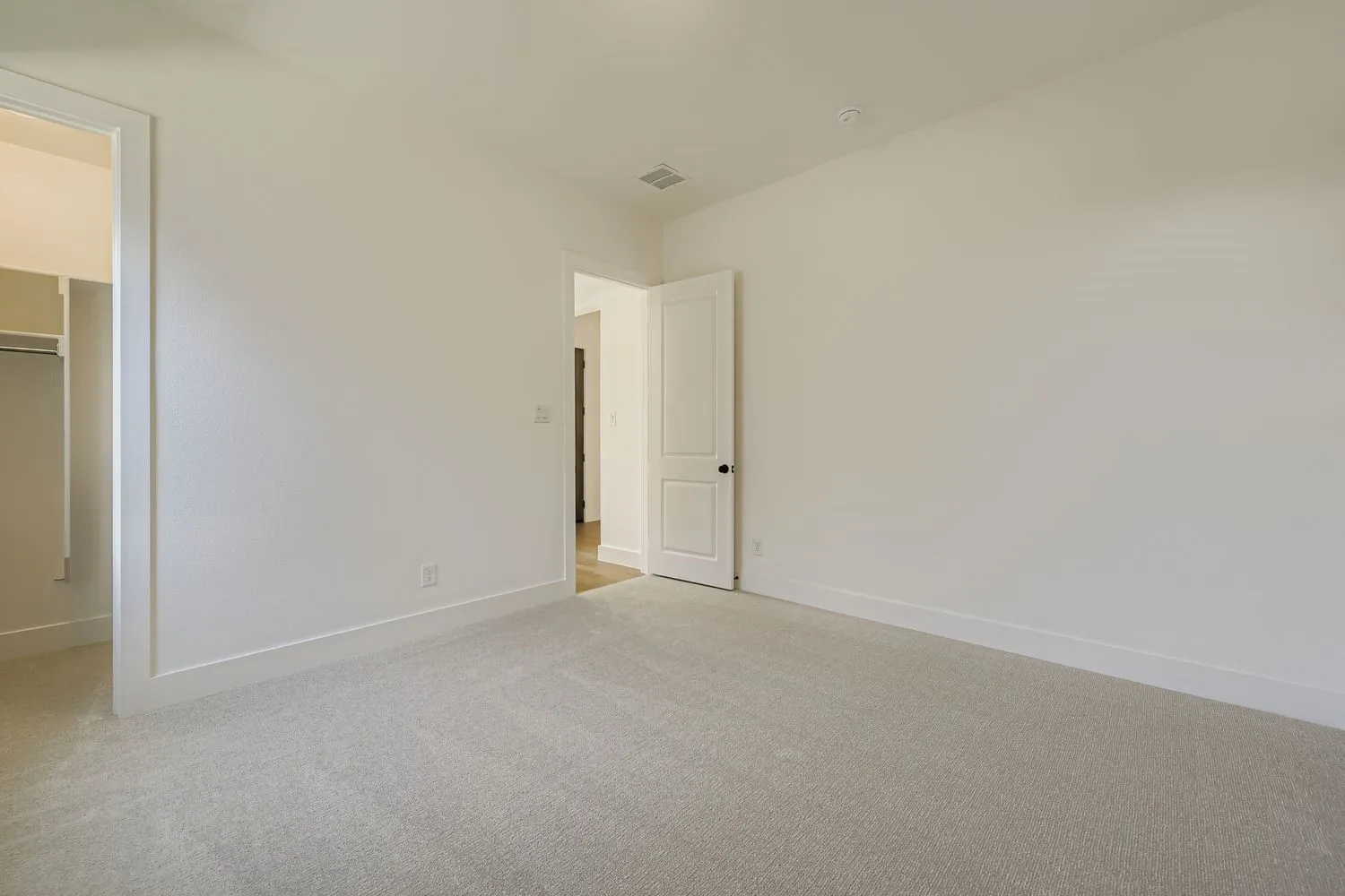 Unfurnished bedroom featuring light carpet and a spacious closet