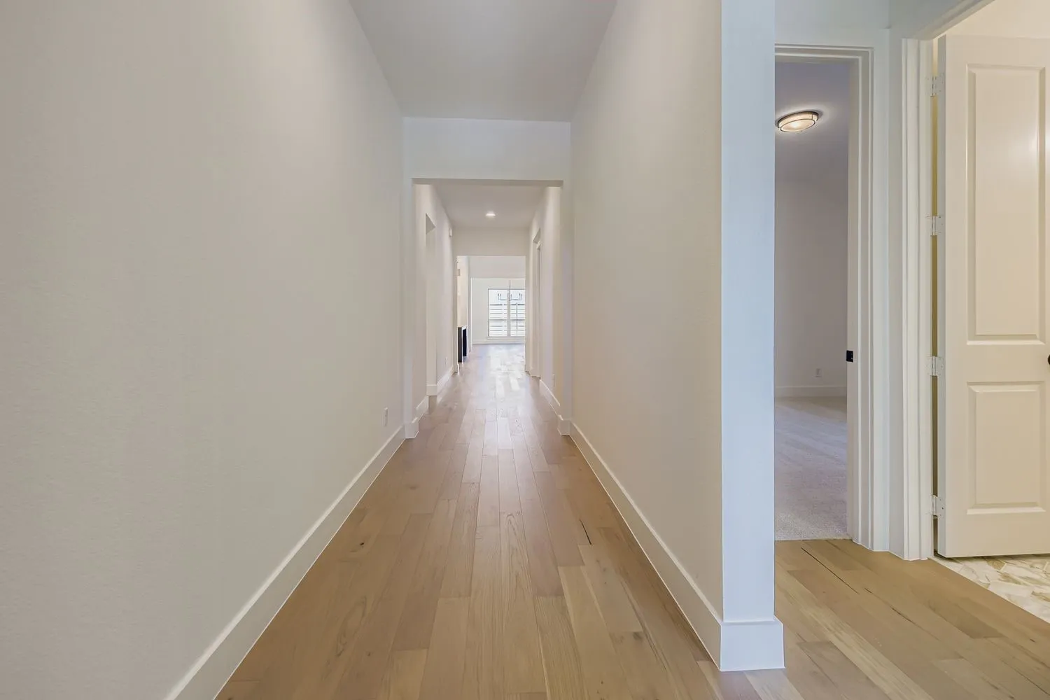 Corridor featuring light wood-style flooring and baseboards
