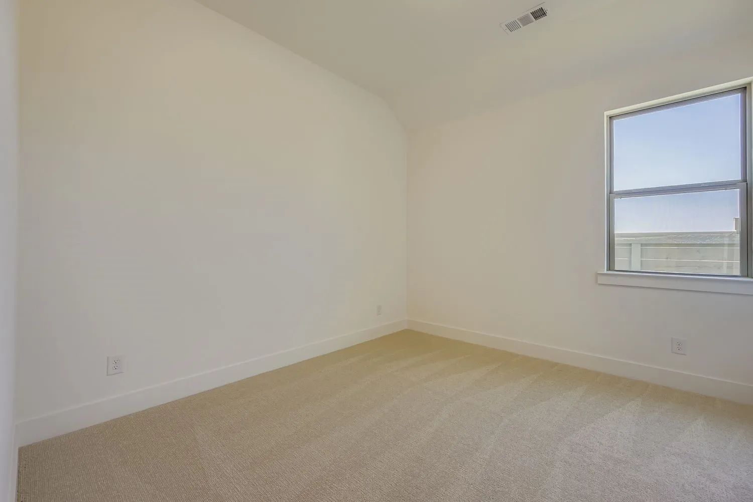 Empty room with light carpet and lofted ceiling