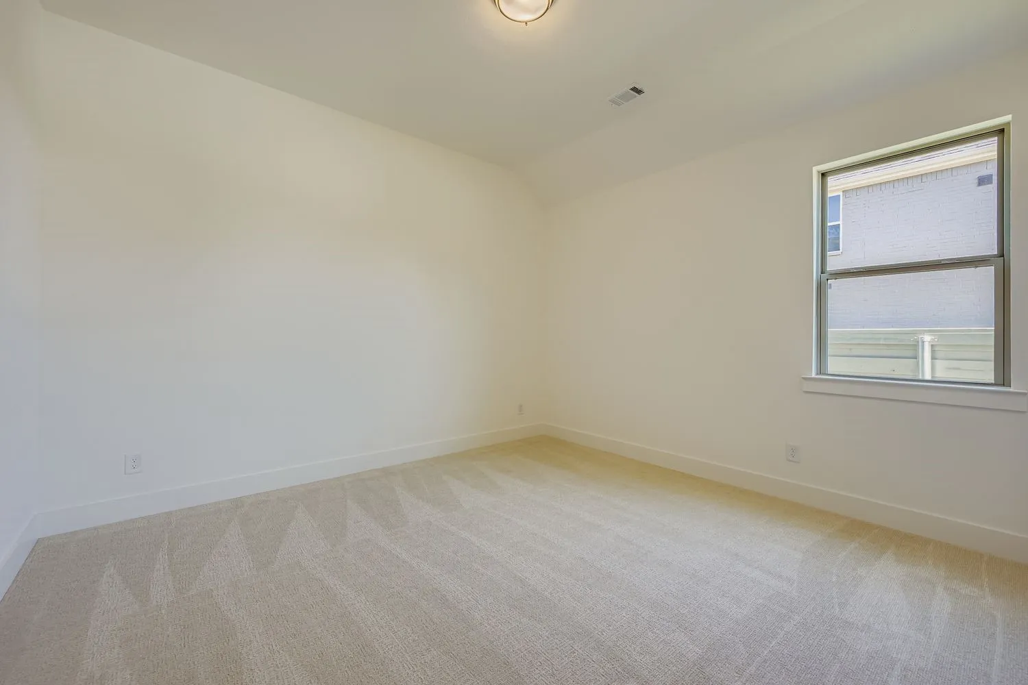 Empty room with light carpet and vaulted ceiling