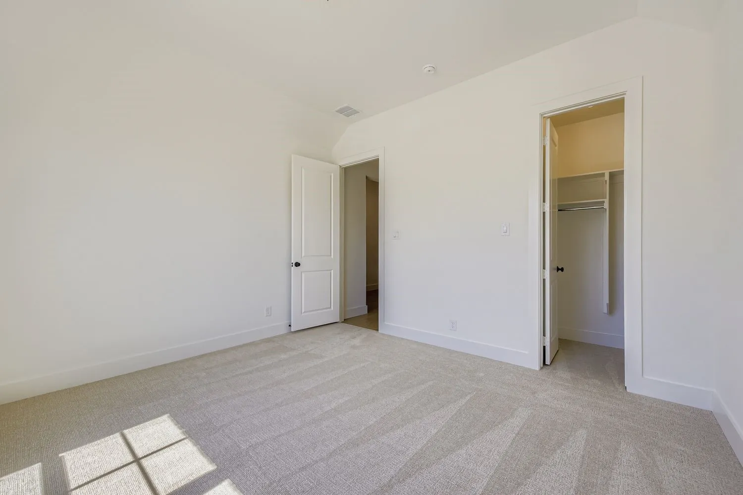 Unfurnished bedroom featuring a walk in closet and light colored carpet
