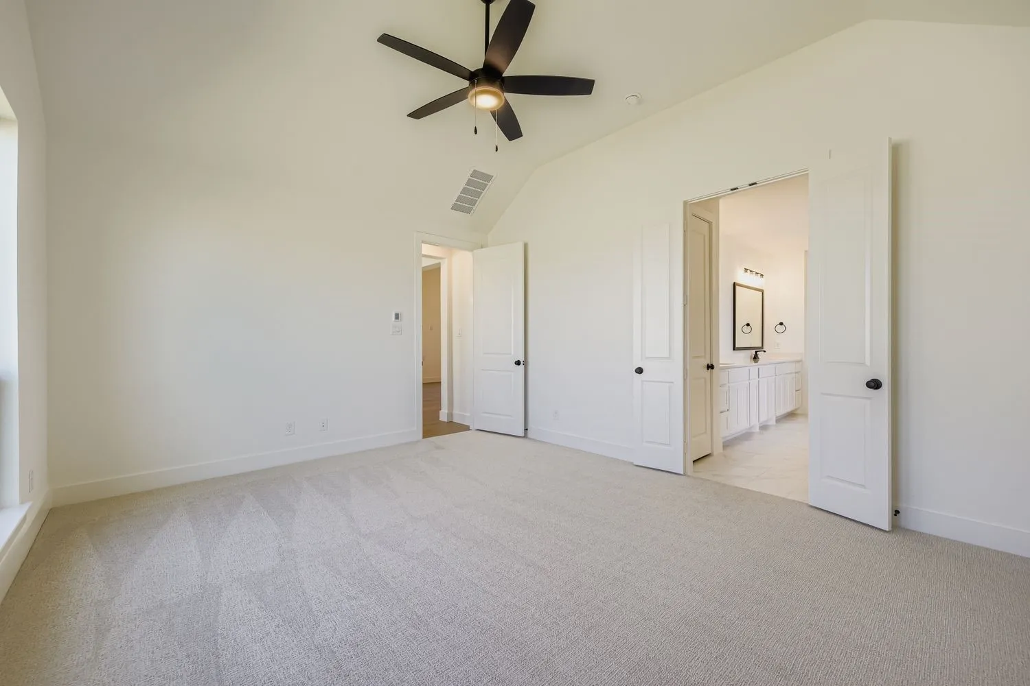 Unfurnished bedroom with light colored carpet, lofted ceiling, ceiling fan, and ensuite bathroom