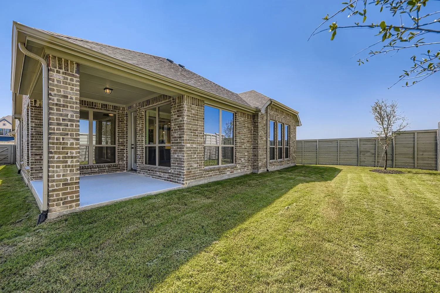 Rear view of property featuring a patio area, brick siding, a shingled roof, and a fenced backyard
