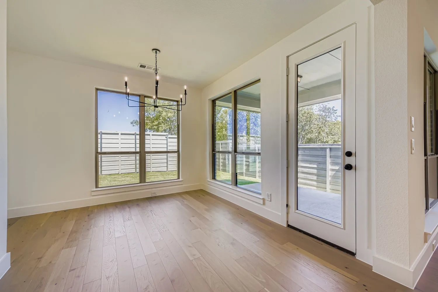 Unfurnished dining area with light wood-style floors, a chandelier, and healthy amount of natural light