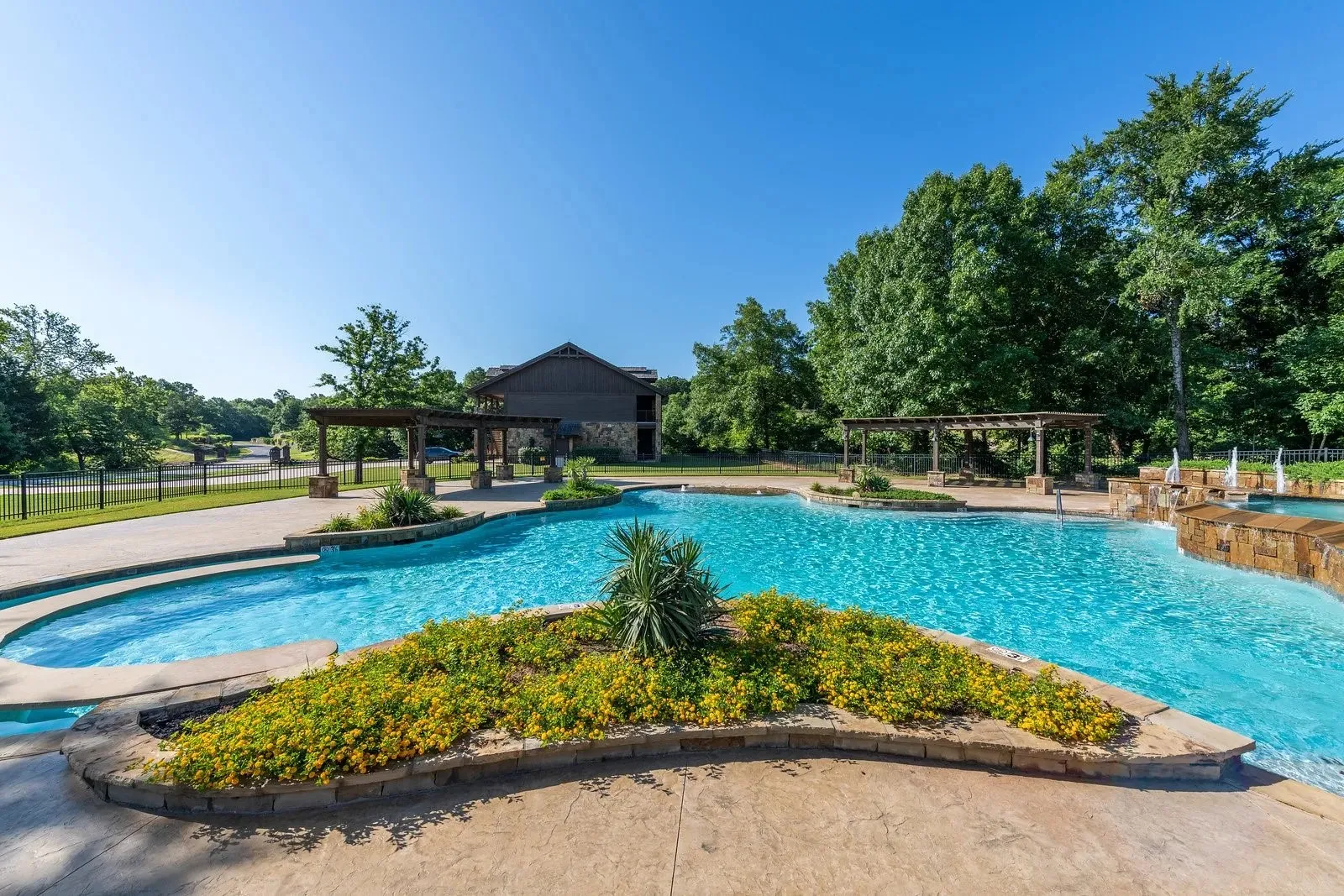 View of swimming pool with a patio area, an outdoor hot tub, and view of wooded area