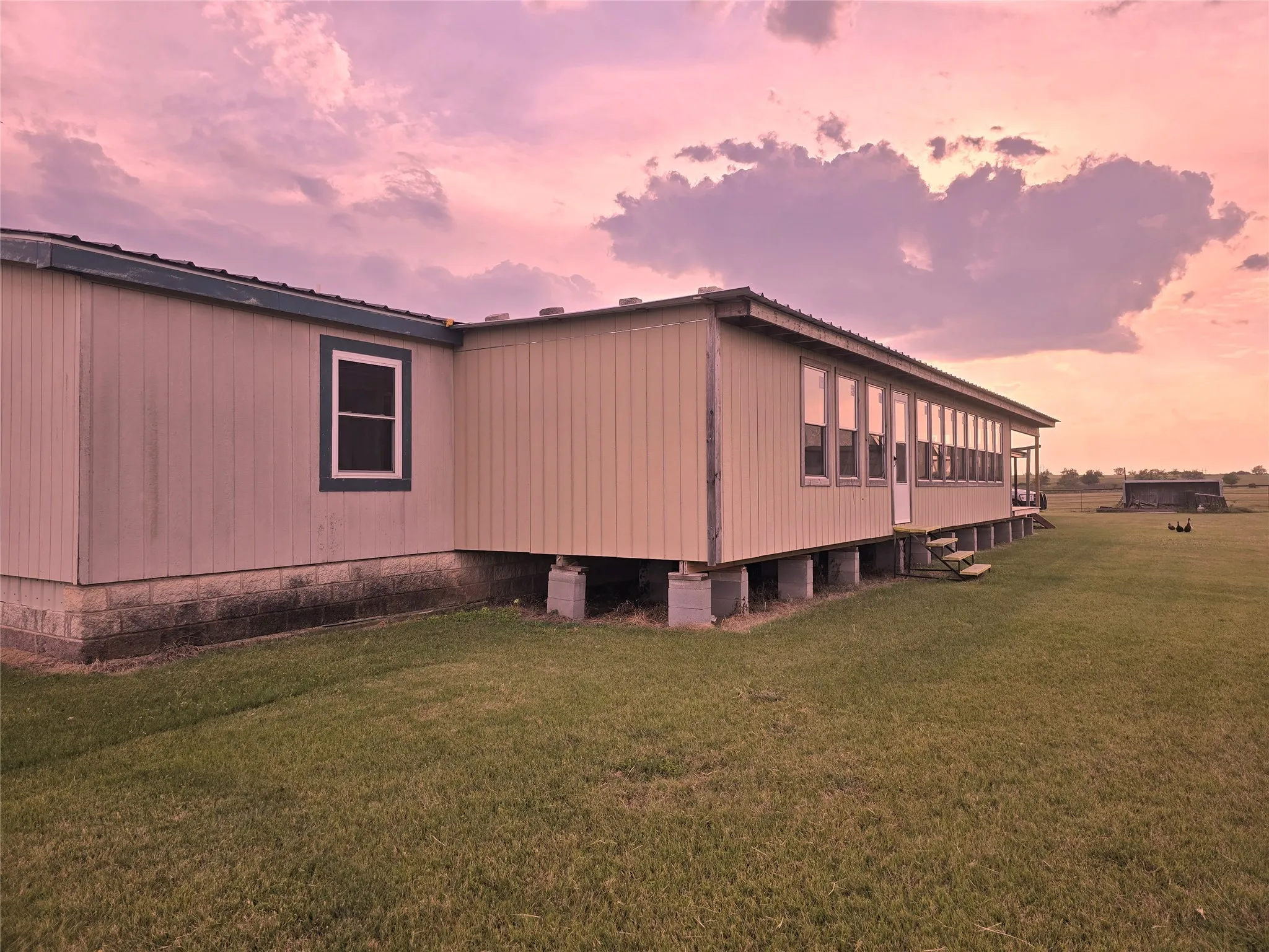 Property exterior at dusk featuring a yard and a metal roof