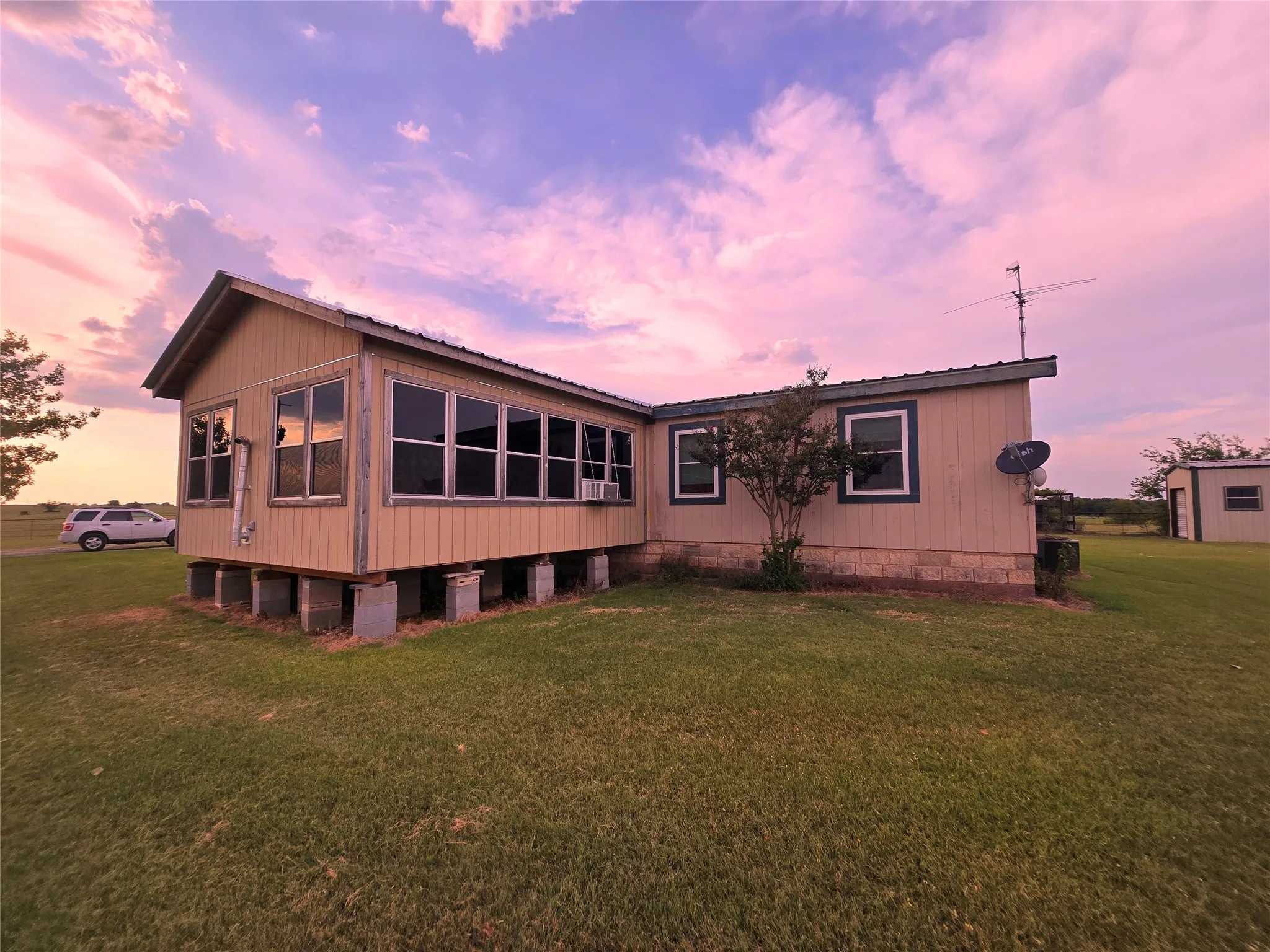 Back of house at dusk with a yard and a metal roof