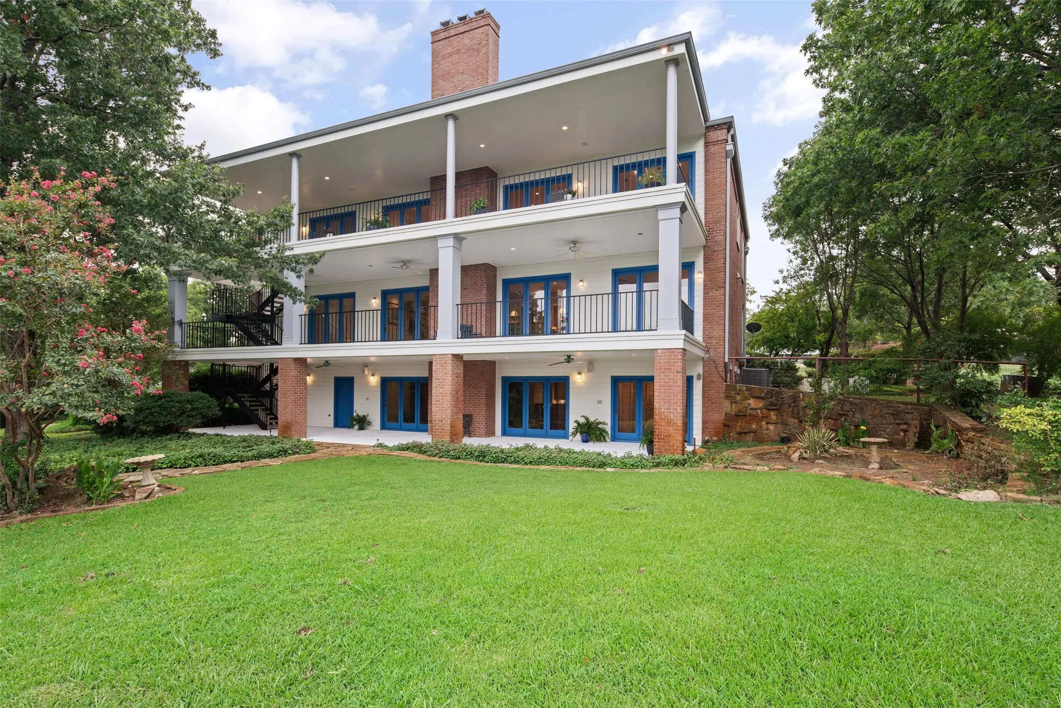 Rear view of house with brick siding, a chimney, a yard, a balcony, and a patio area