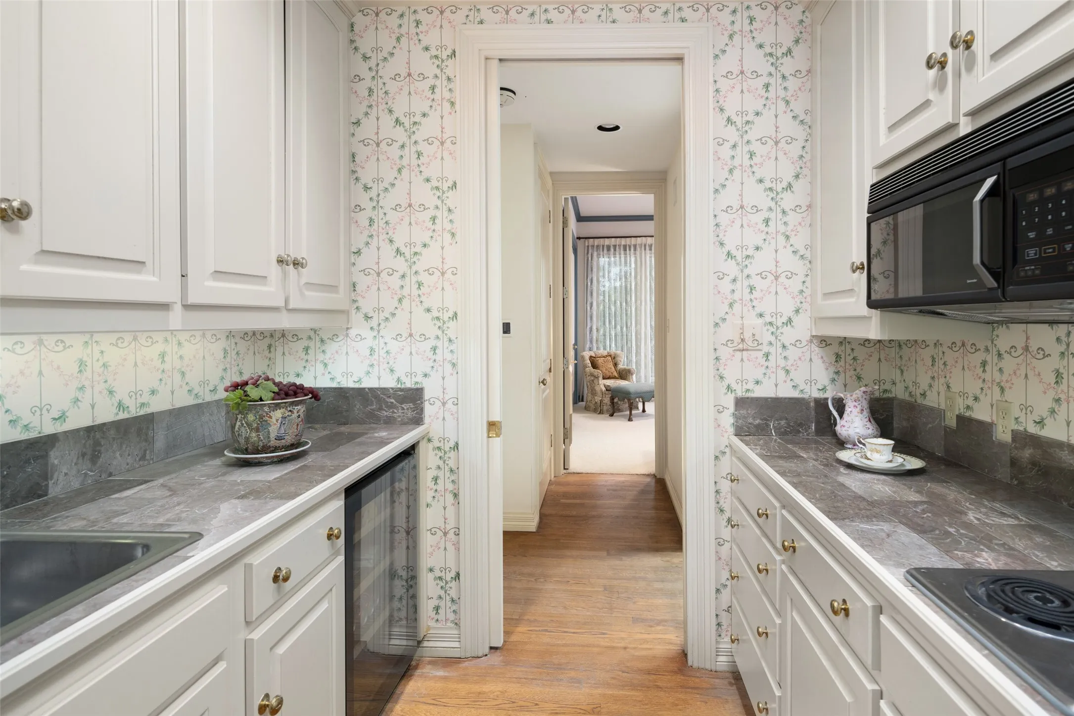 In- law Kitchen featuring white cabinetry, marble countertops, beverage cooler, stainless sink, microwave and an electric cooktop.