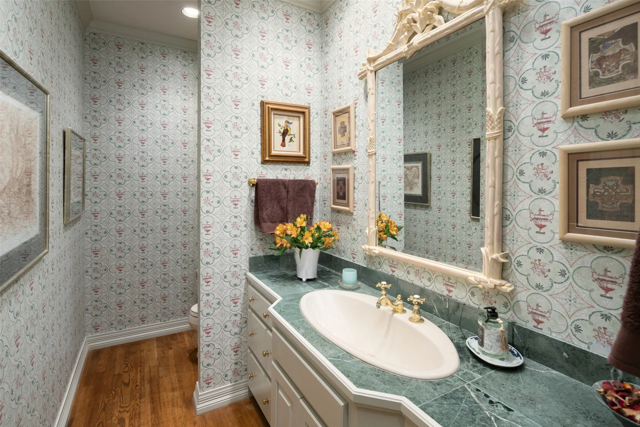 Half bathroom with beautiful wallpapered wall and marble vanity located on the second level.