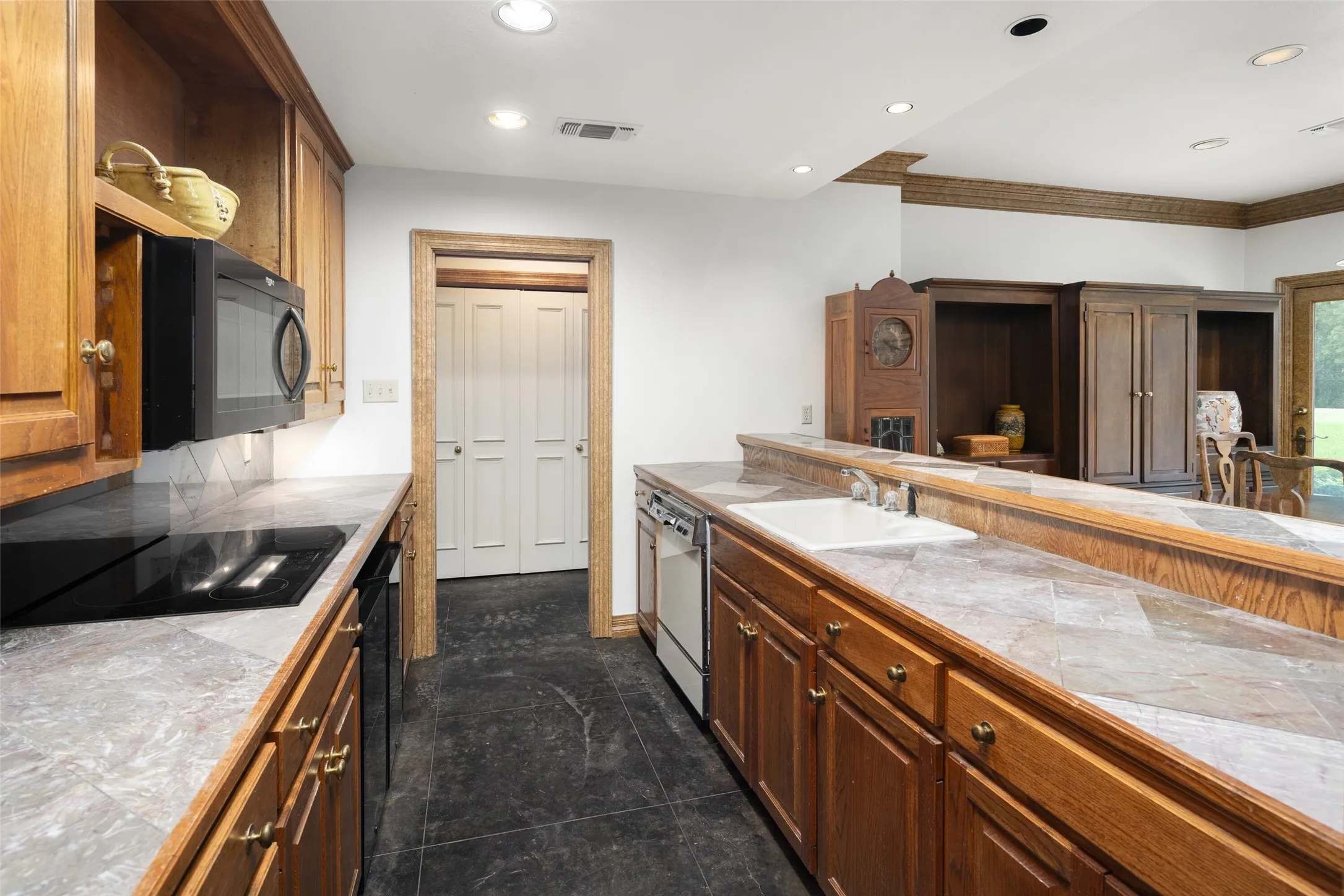 Kitchen featuring recessed lighting, black appliances, brown cabinets, and dark tile patterned floors