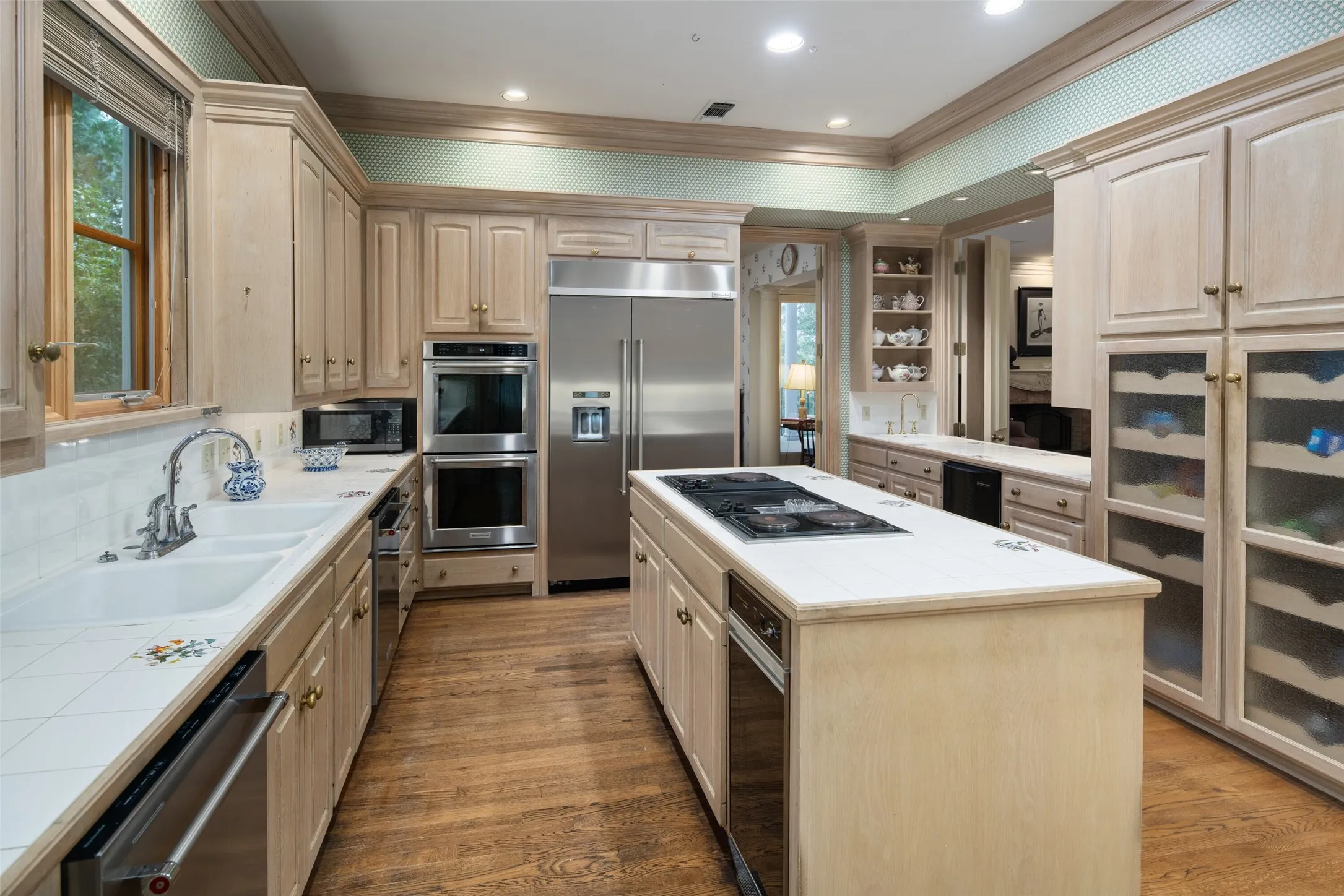 Kitchen featuring tile countertops, stainless steel double oven, sub zero refrigerator and an island with an electric cooktop which opens up to the living area on the third level.