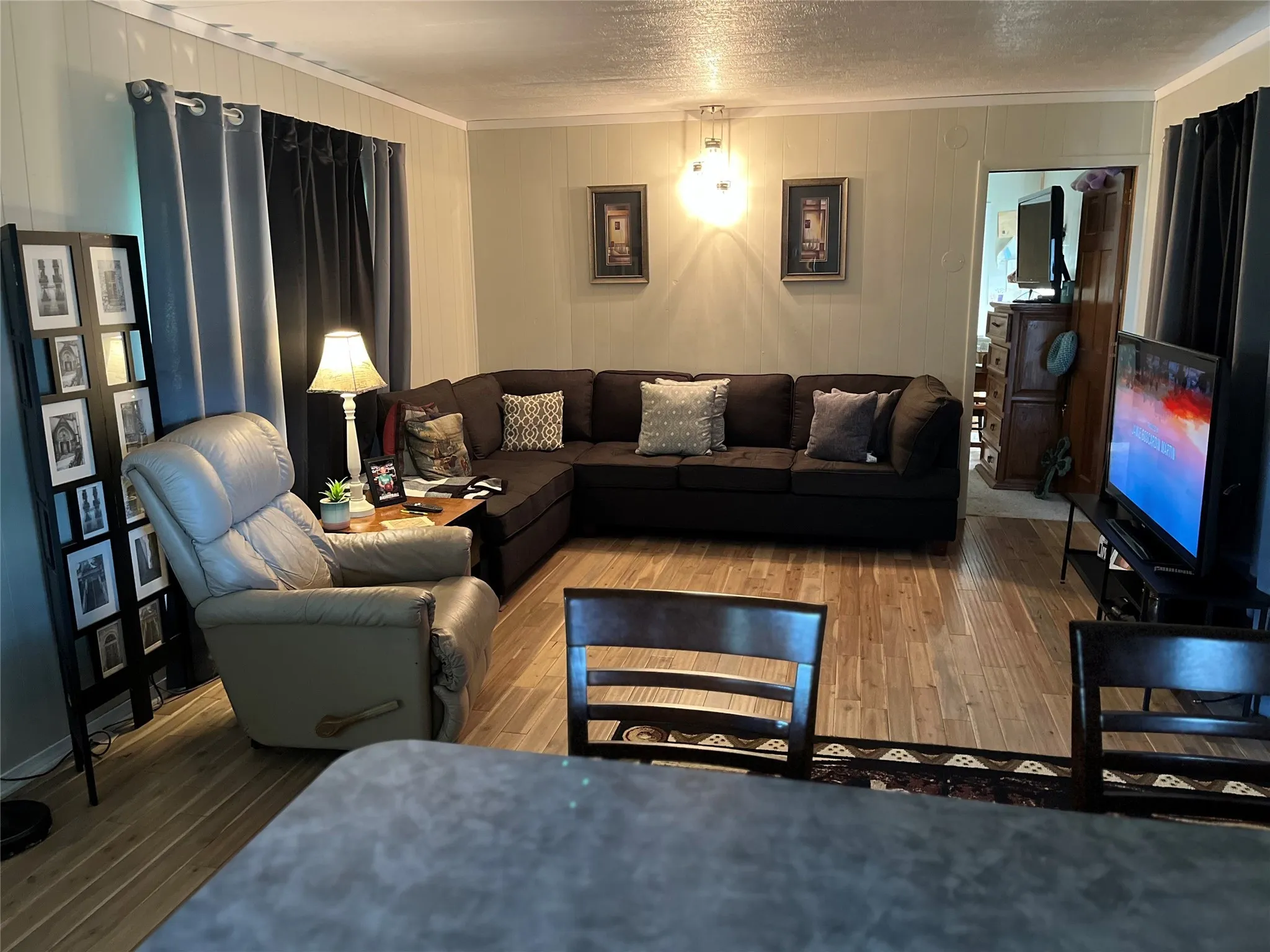 Living room with crown molding, wood finished floors, a textured ceiling, and wooden walls